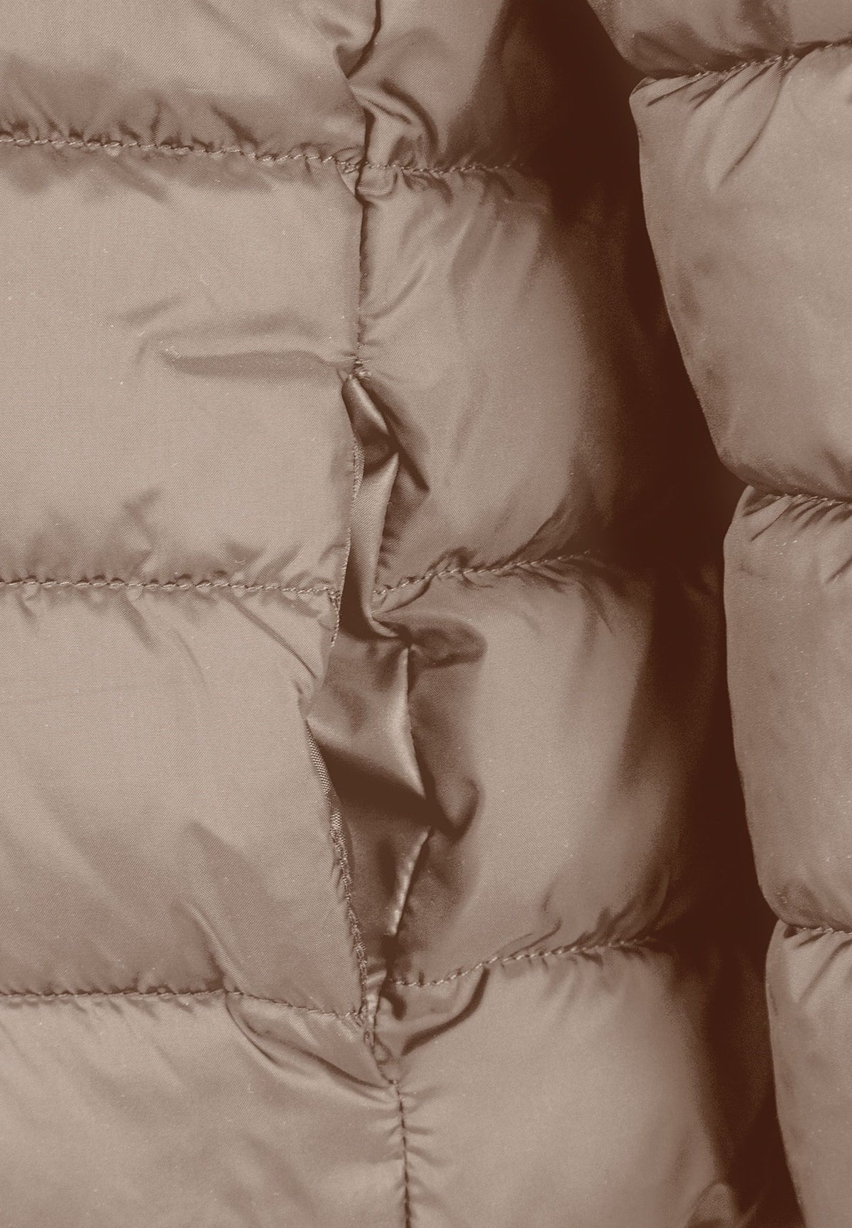 Close-up of a side pocket opening on the beige padded jacket.