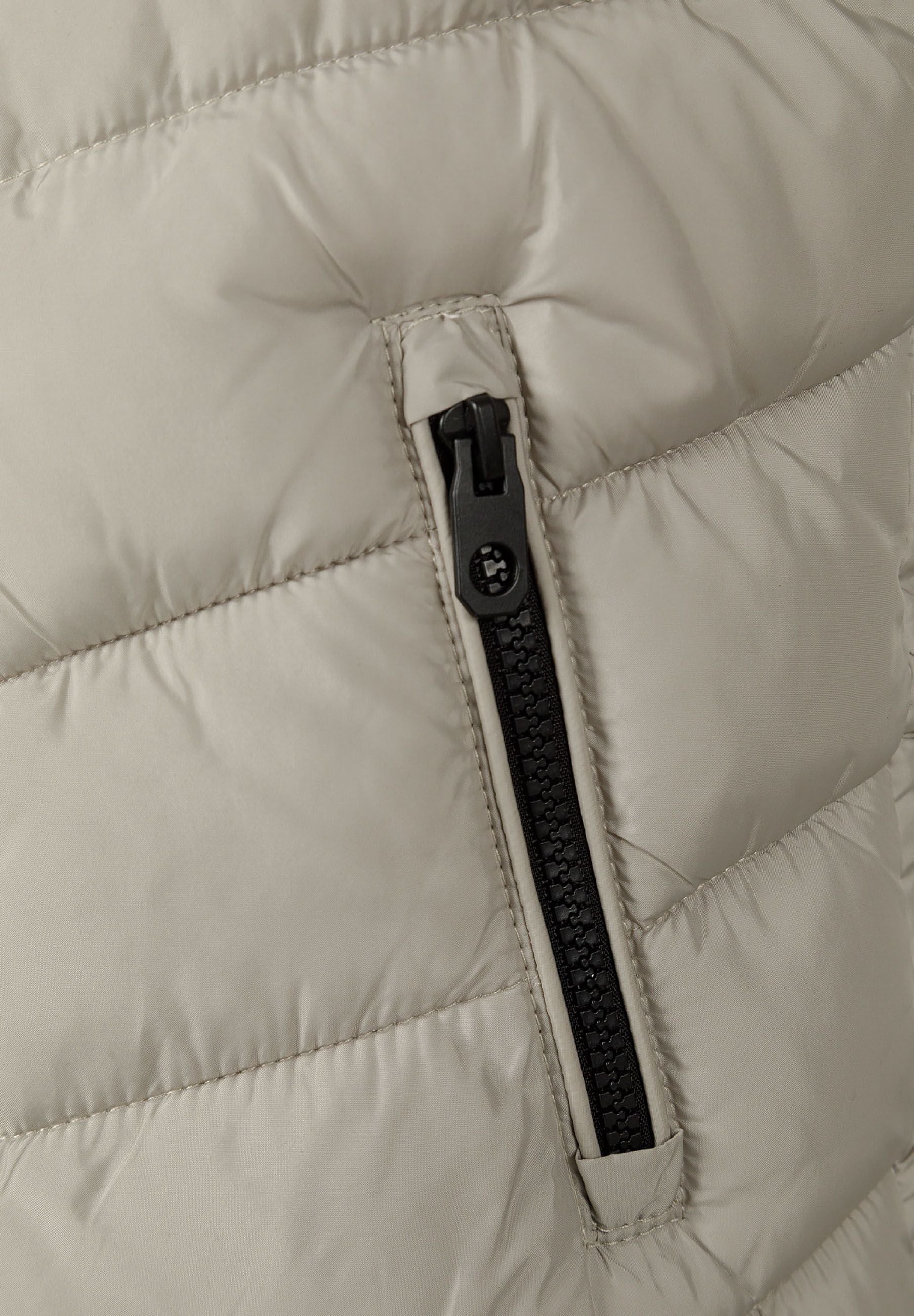 Detail of boys gilet with full-length zip and padded texture.