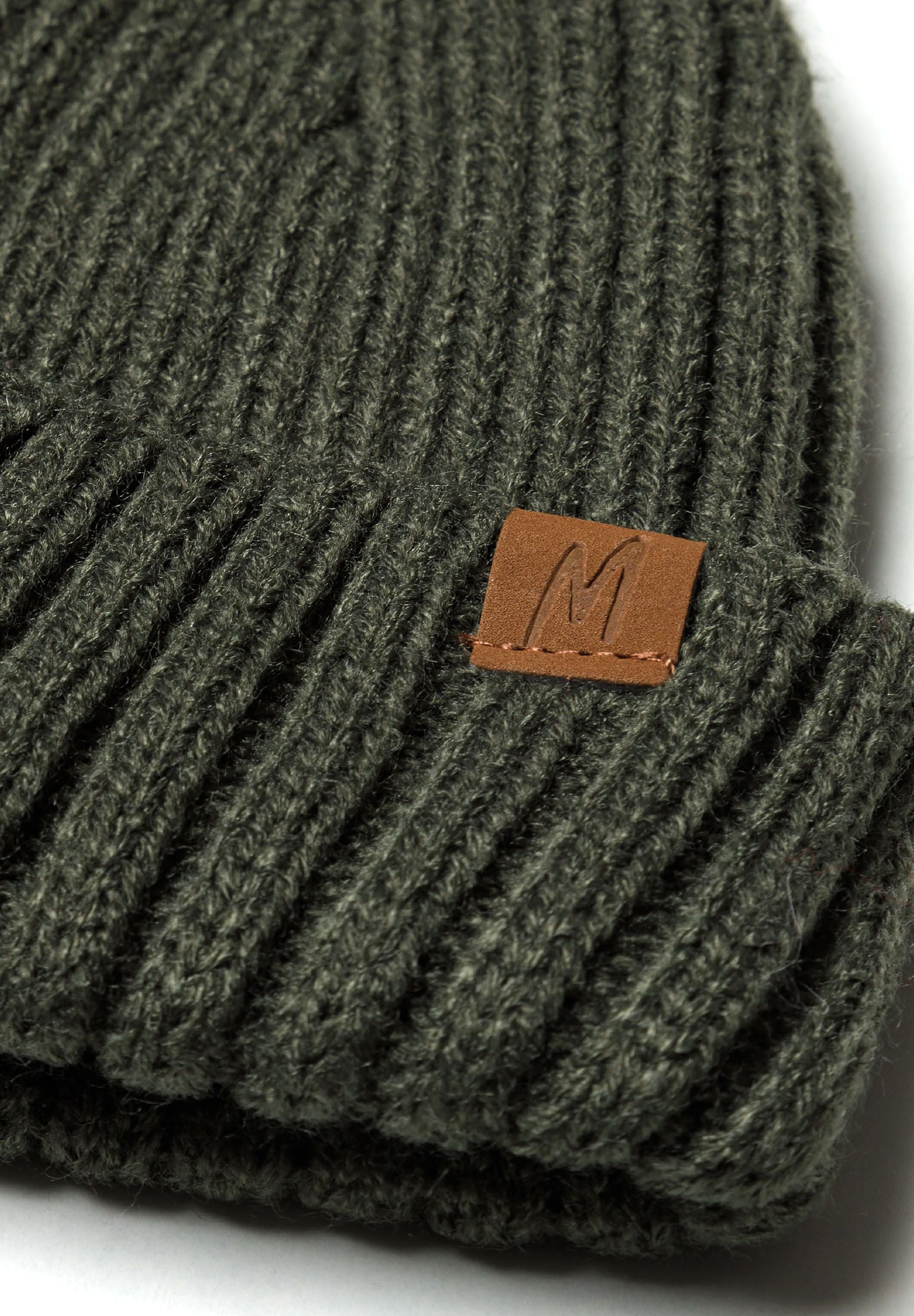 Detail of a khaki knitted rib beanie with a fold-over brim and logo badge.