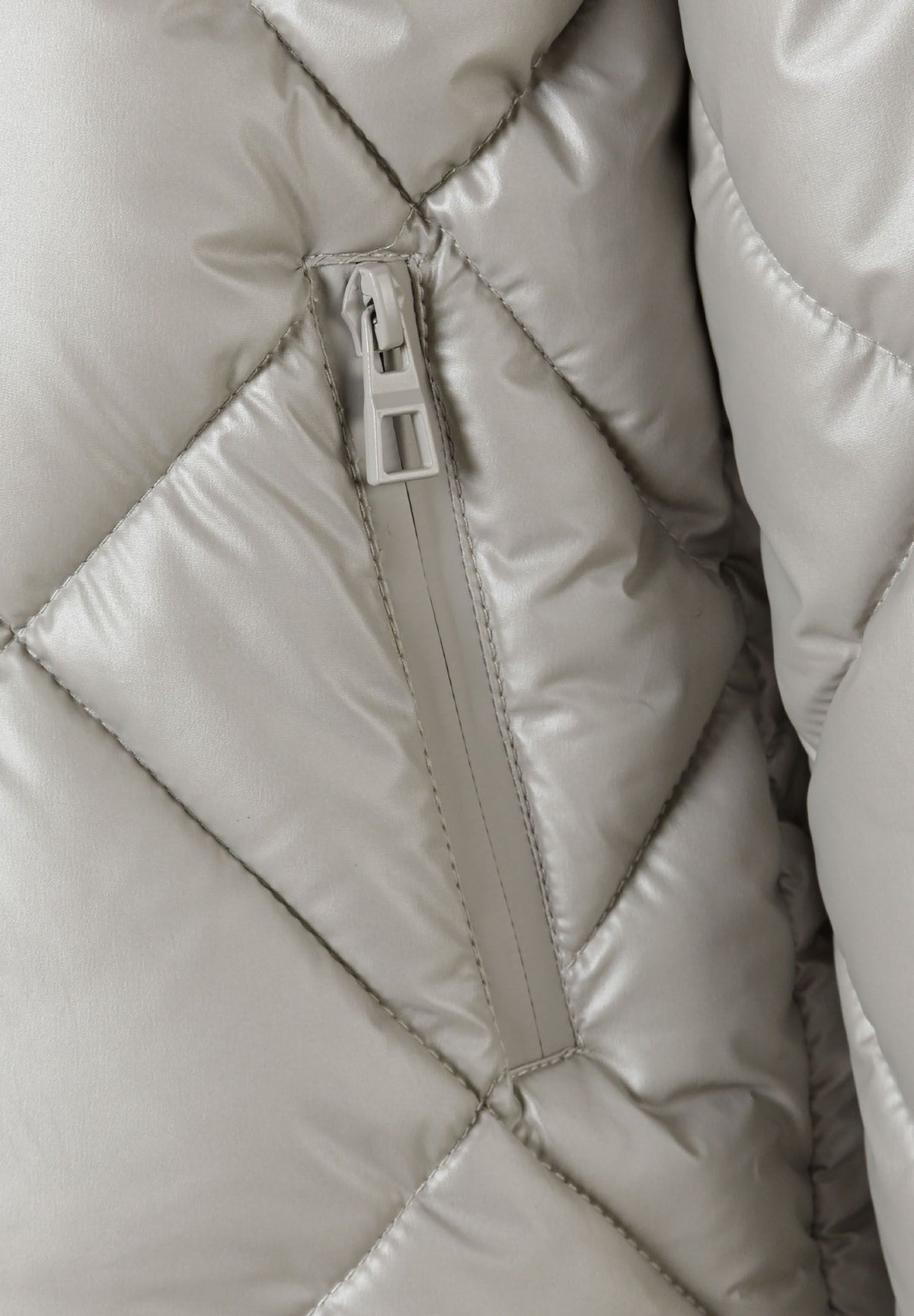 Close-up of a vertical zipped pocket in silver diamond-quilted jacket fabric.