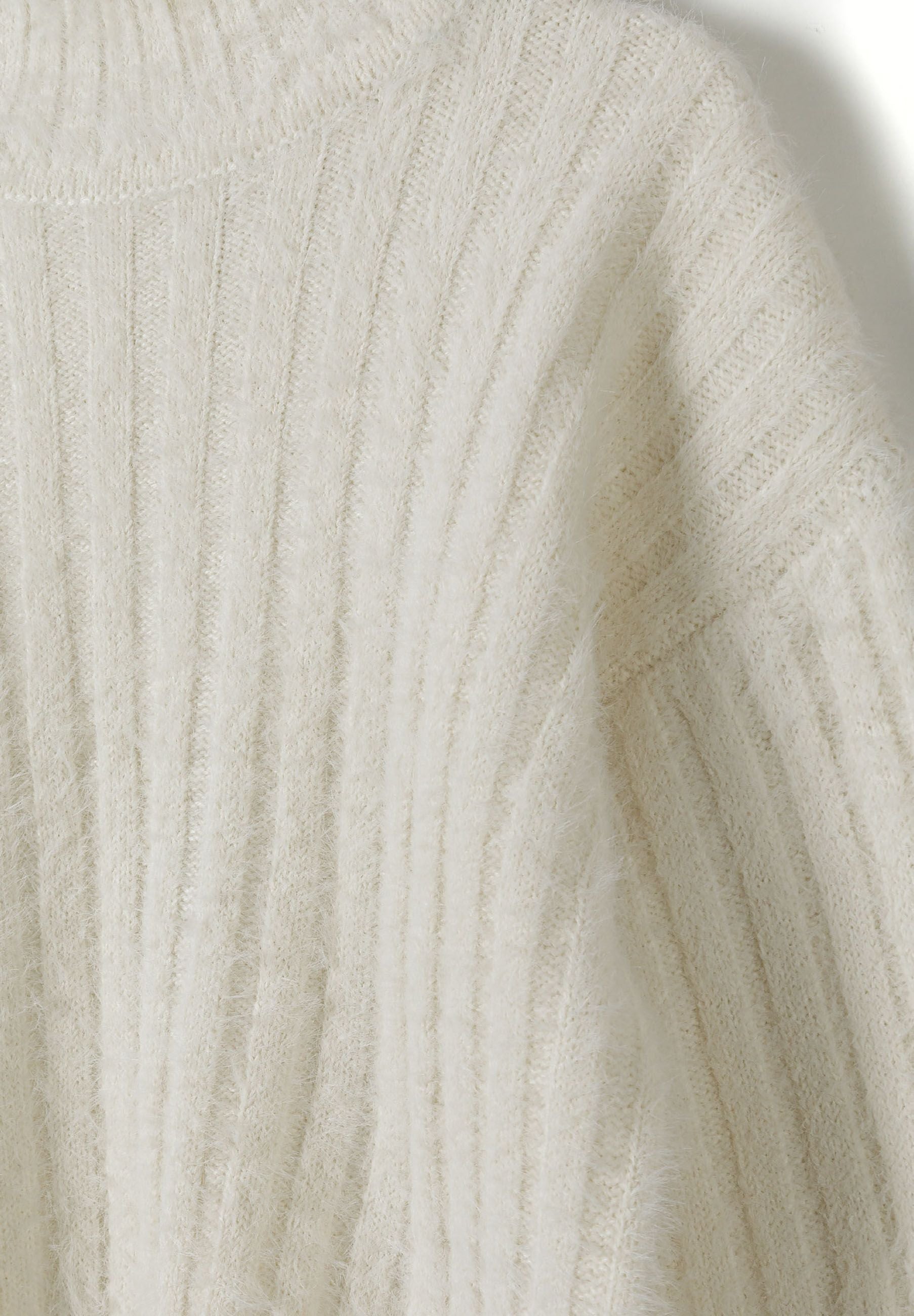 Detail of a cream girls jumper with high neck and ribbed texture.