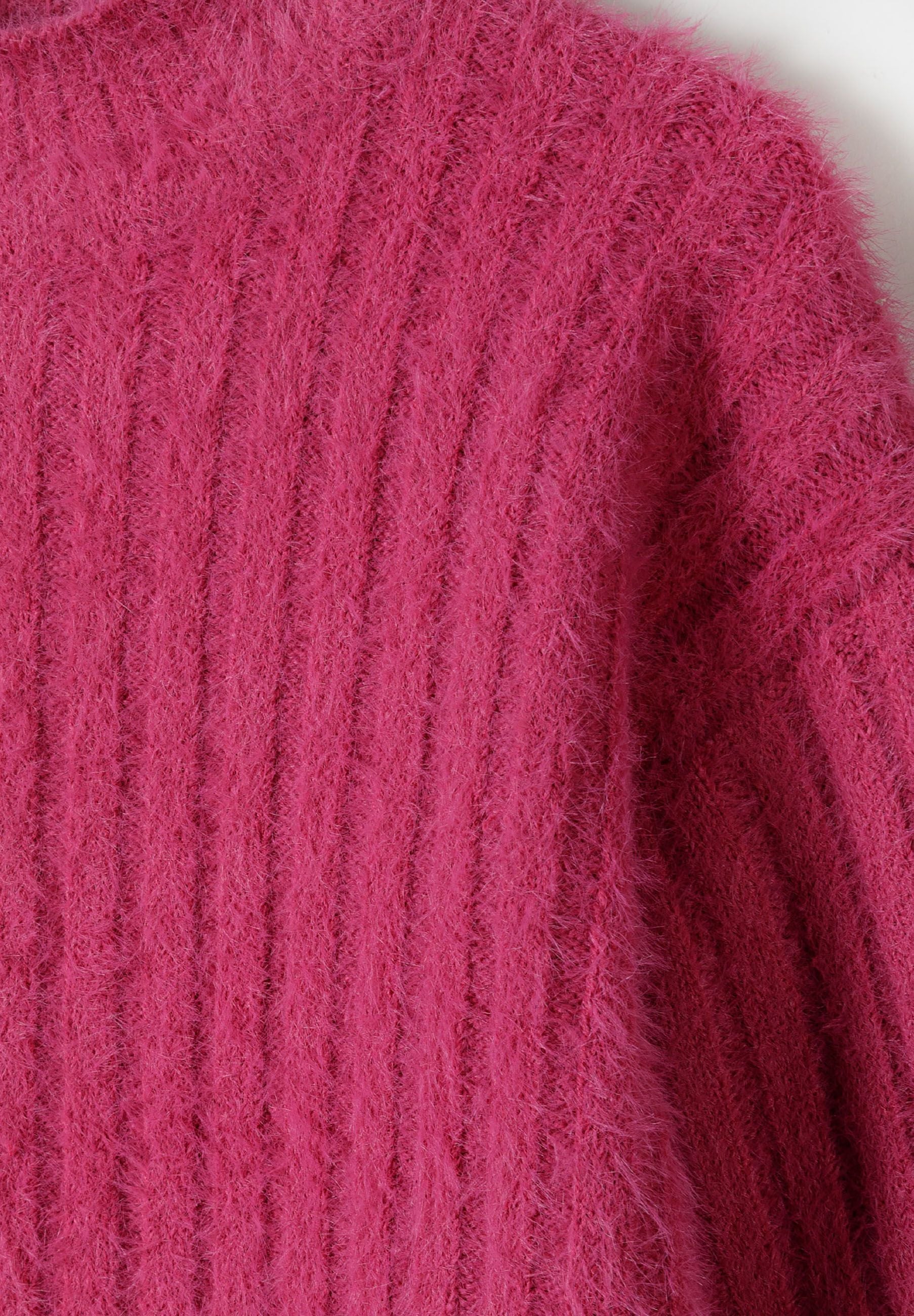 Close-up of a pink girls jumper with a high neck and ribbed texture.