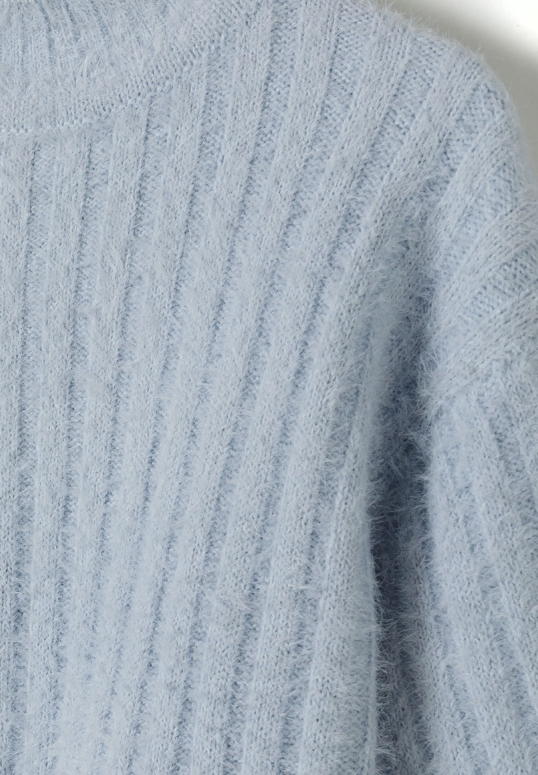Detail of a girls high neck jumper in soft fluffy blue with ribbed texture.