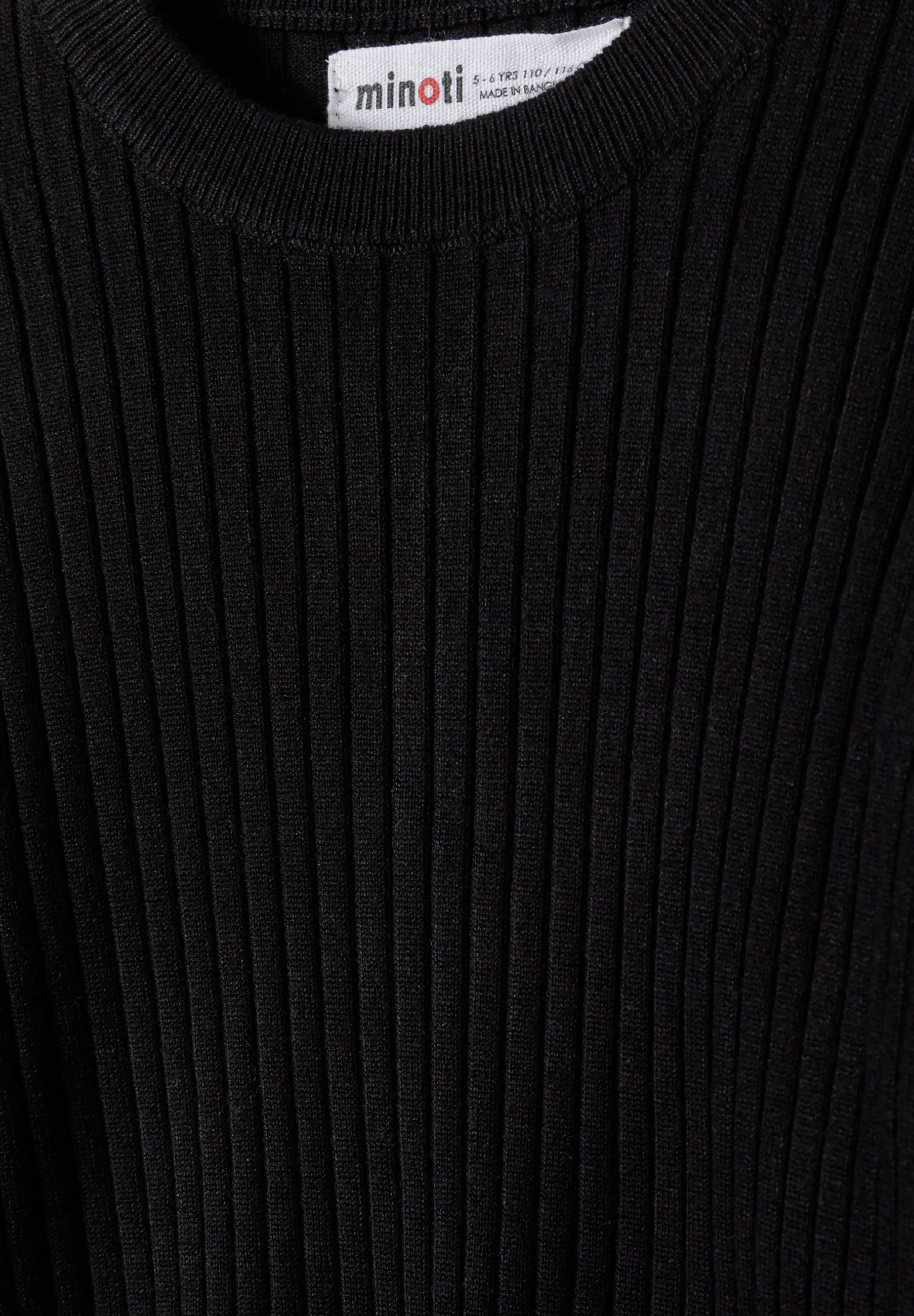 Close-up of a black ribbed long sleeve jumper with frill cuffs.