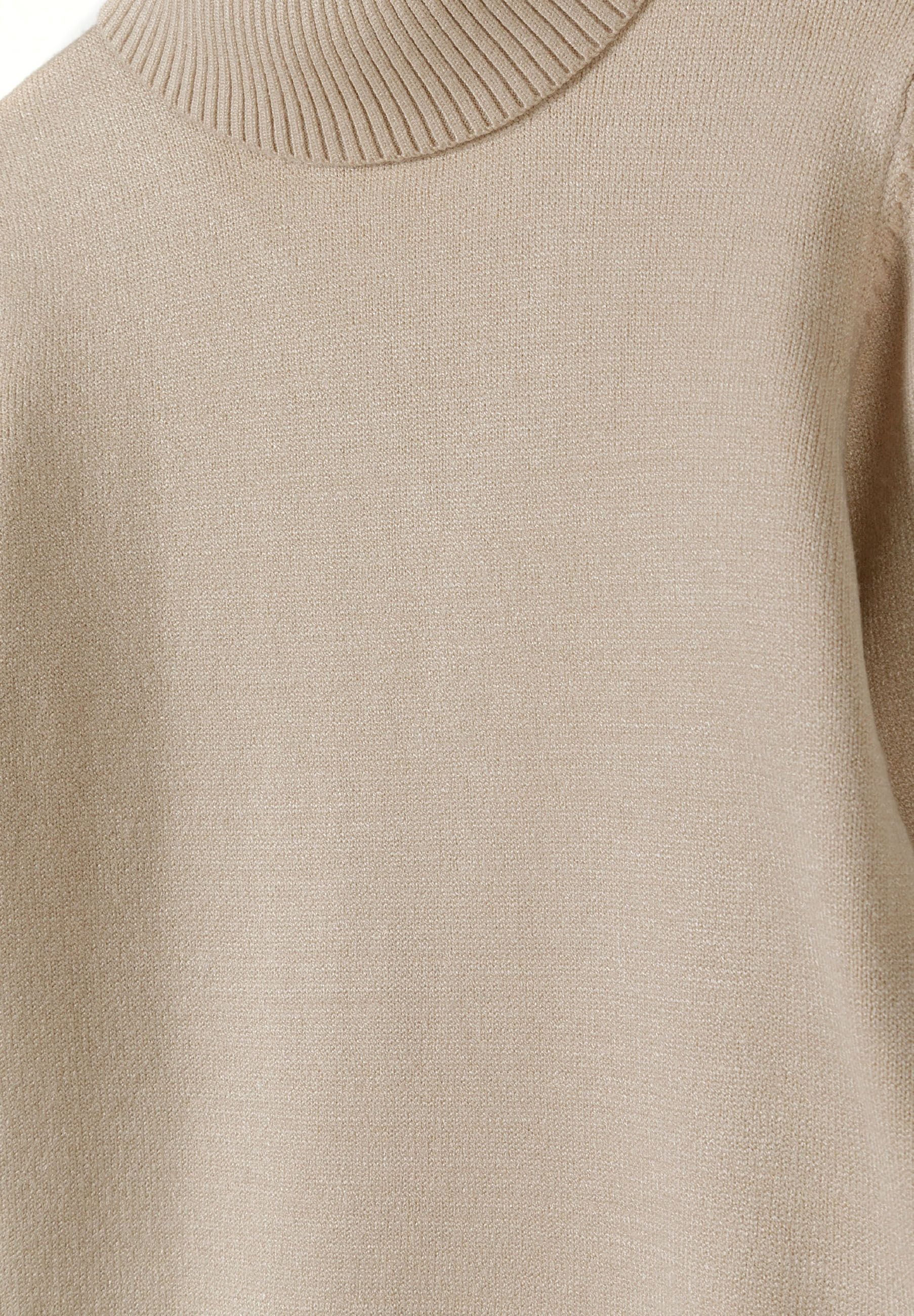 Detail of a beige girls turtleneck jumper with ribbed collar.