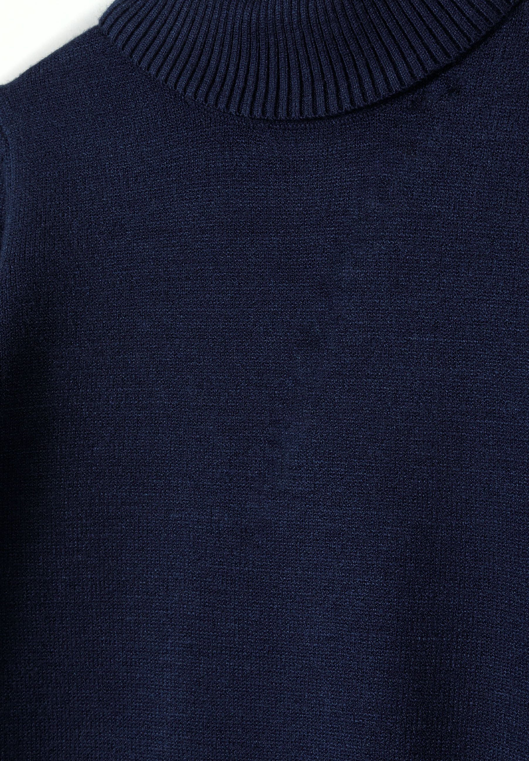 Detail of a navy girls turtleneck jumper with ribbed collar.