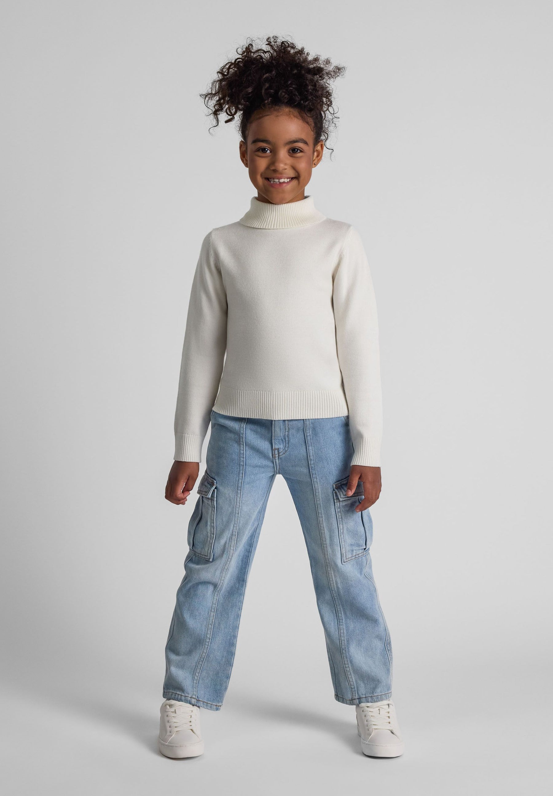 Girls cream turtleneck jumper, front view, featuring long sleeves and ribbed cuffs.
