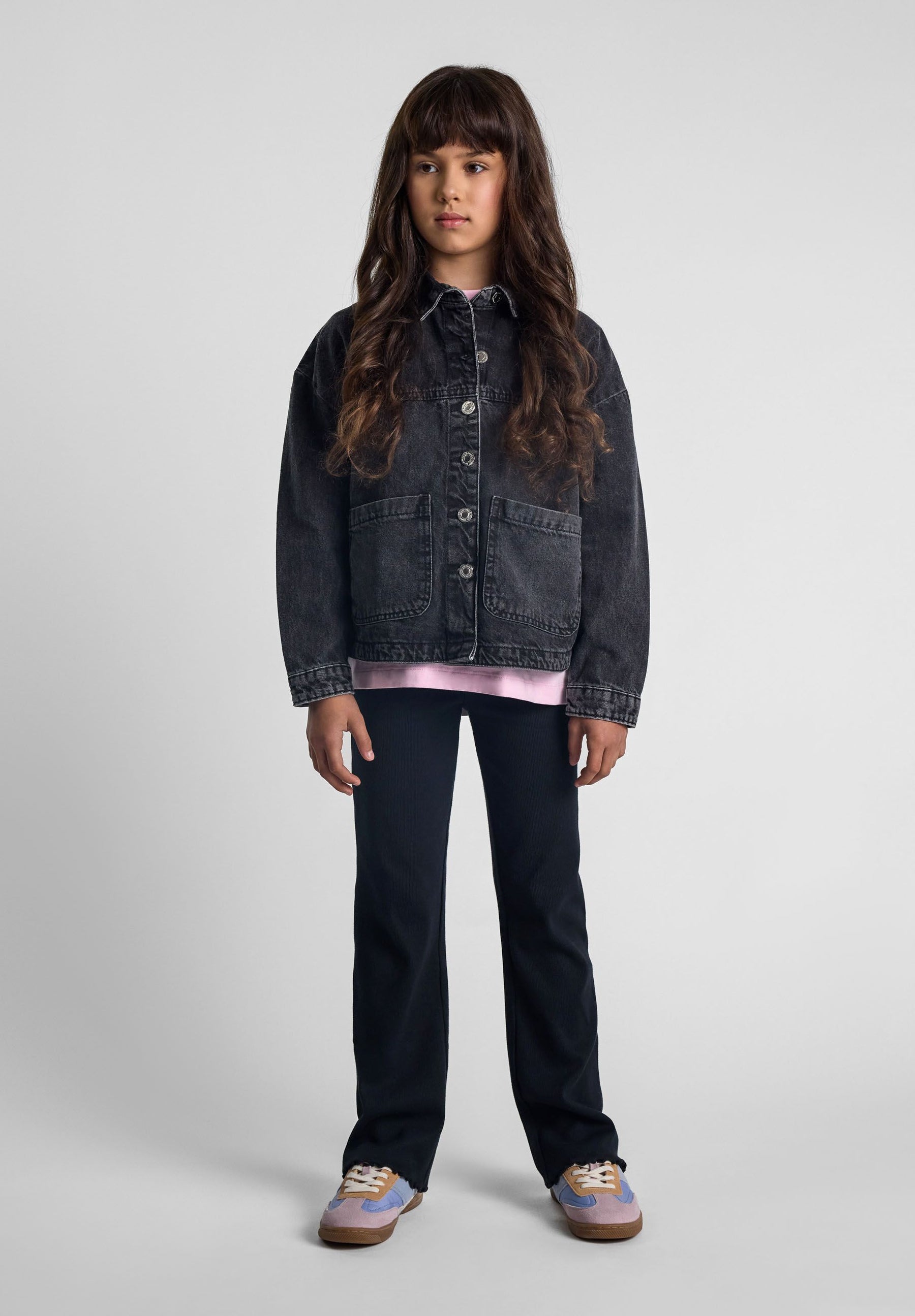 Girls black denim jacket, front view, with button closure and two large pockets.