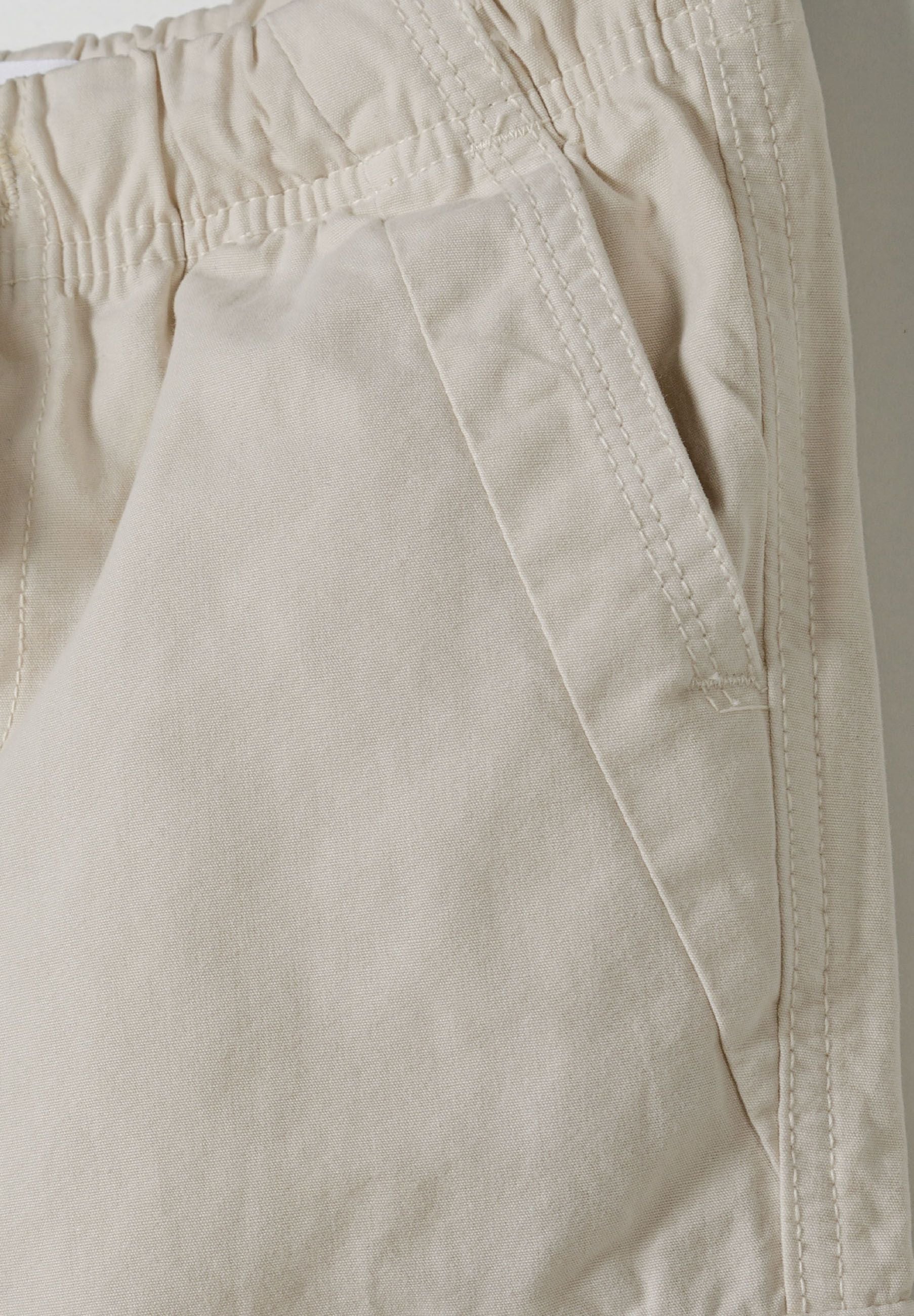 Detail of girls' cargo pants with elasticated waist and side pocket.