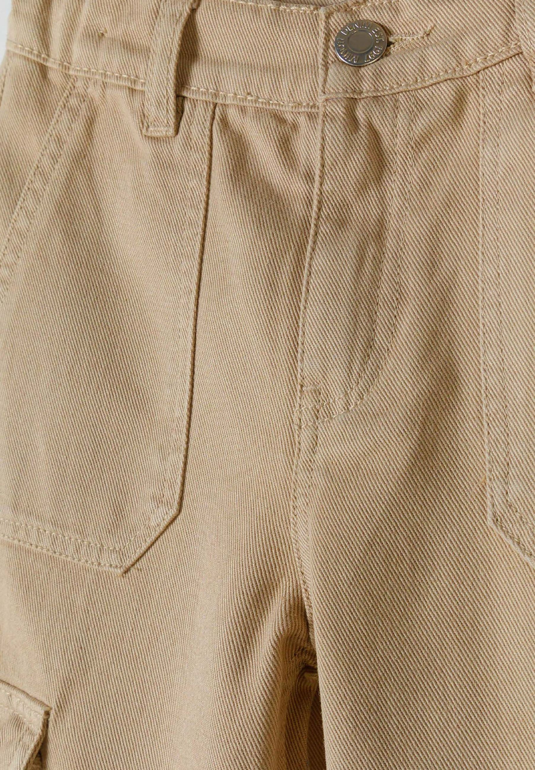 Detail of beige wide-leg combat pants with front and side pockets.