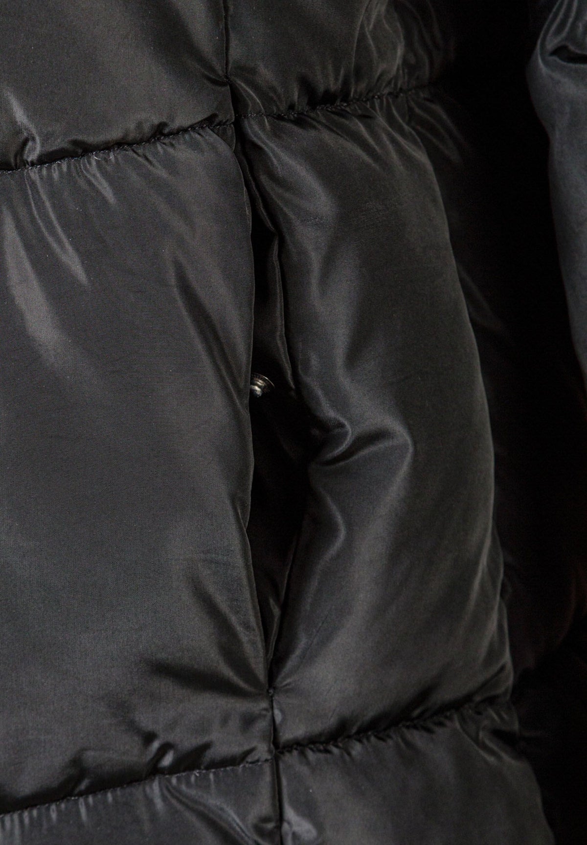 Close-up of the pocket on the black long puffer coat.