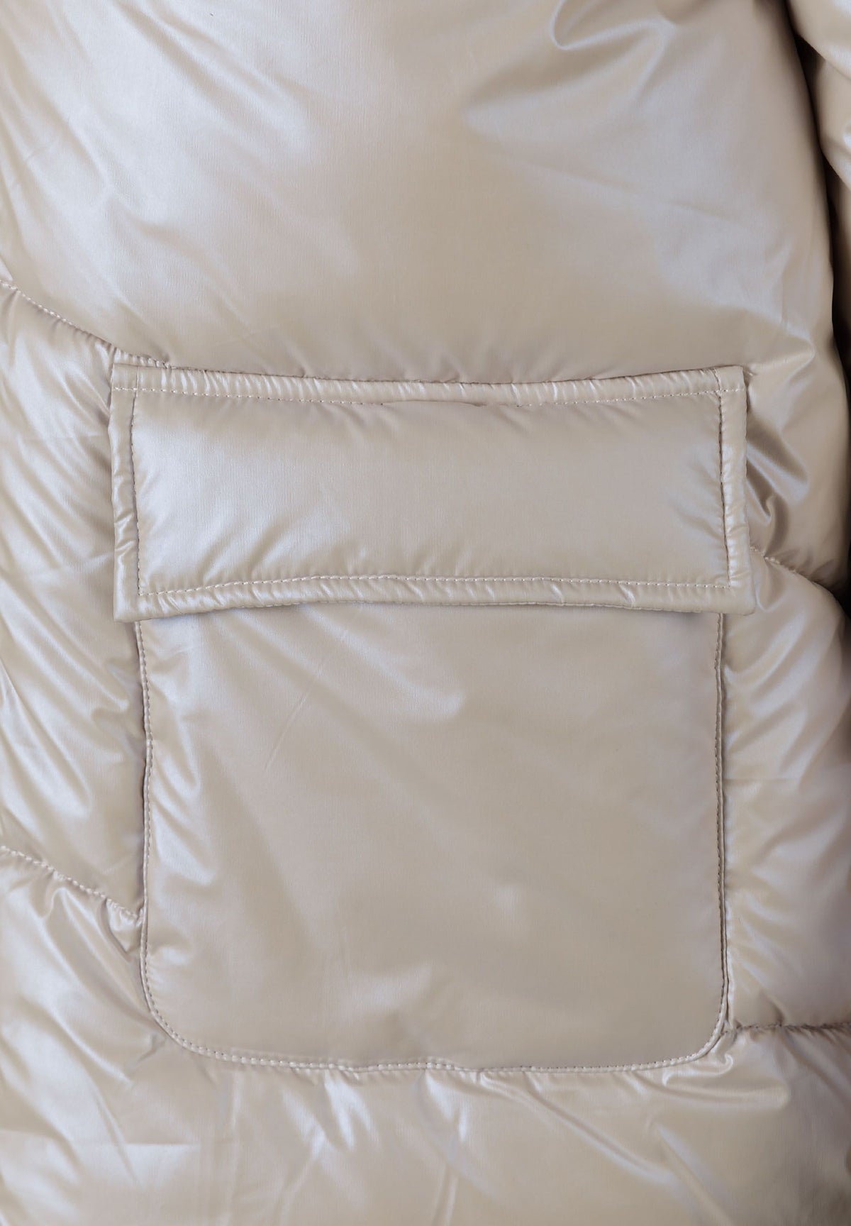 Close-up of the pocket on the light beige puffer jacket.