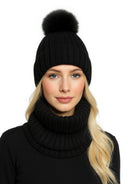 Close-up of a black knitted beanie with faux fur pom pom and matching snood.