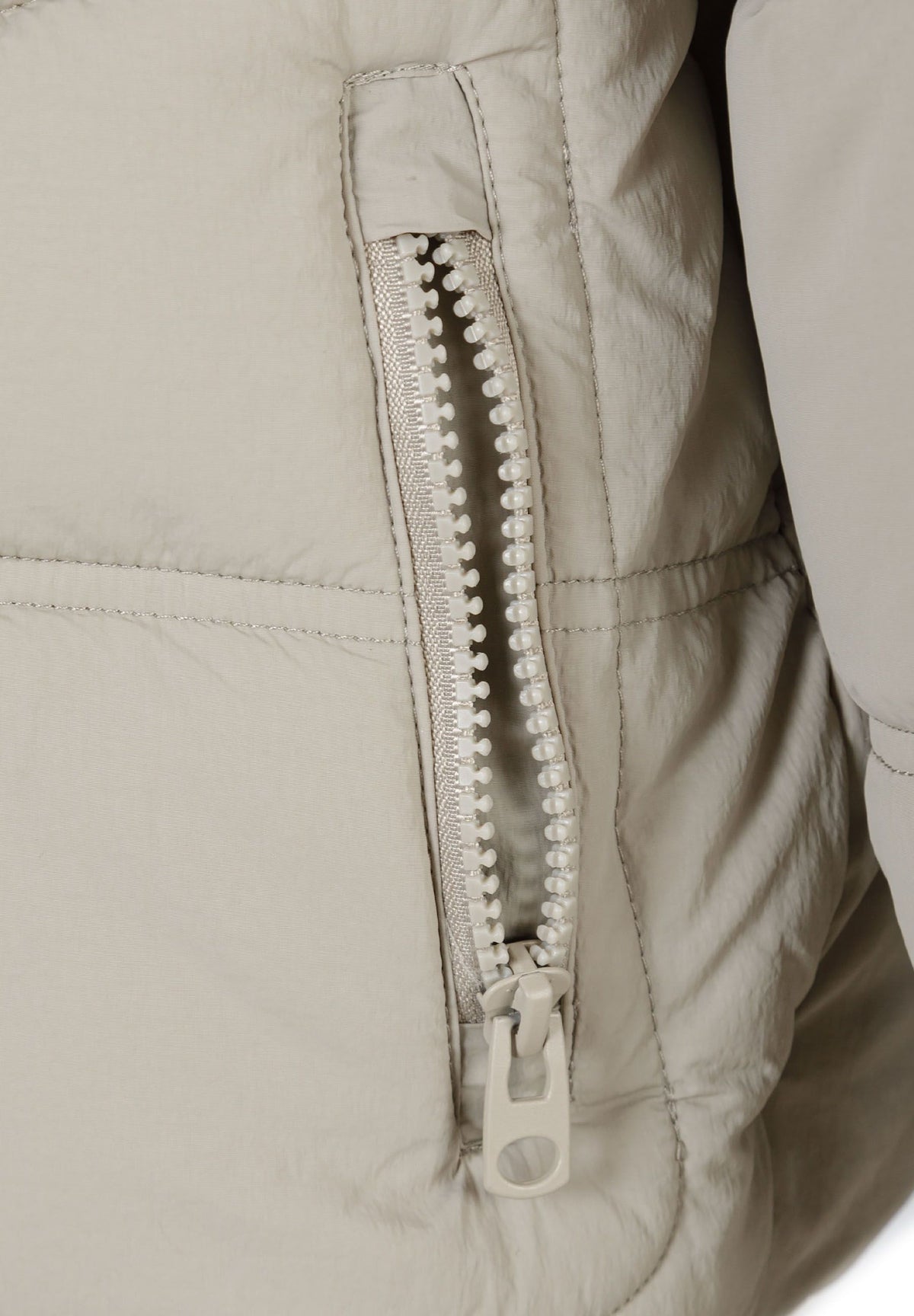 Close-up of the zipped pocket on the stone puffer jacket.