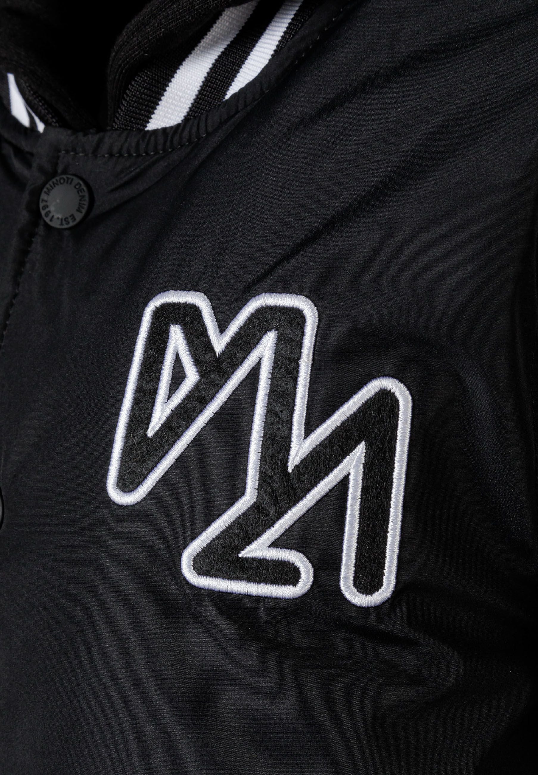 Detail of a black boys baseball jacket featuring embroidered logo and button closure.
