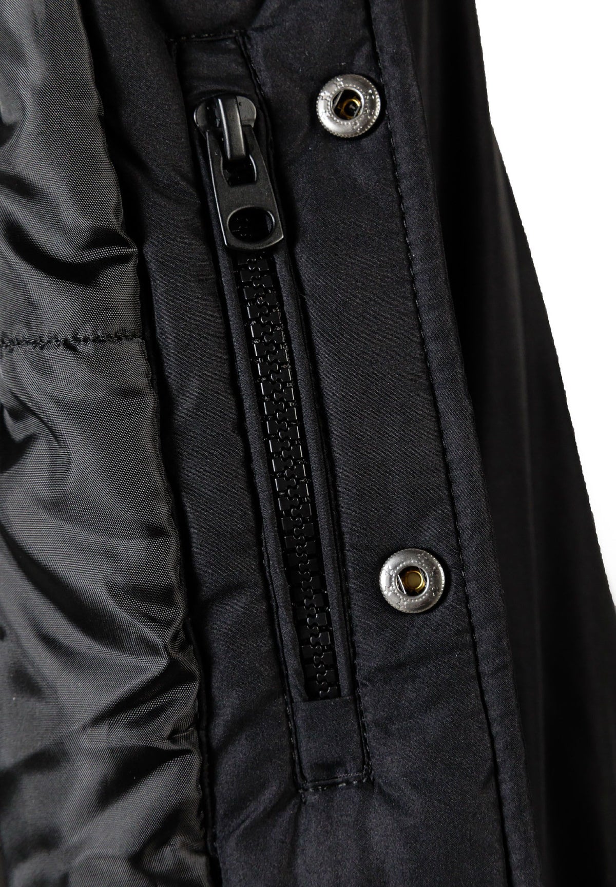 Close-up of the zip and popper on the black varsity jacket.