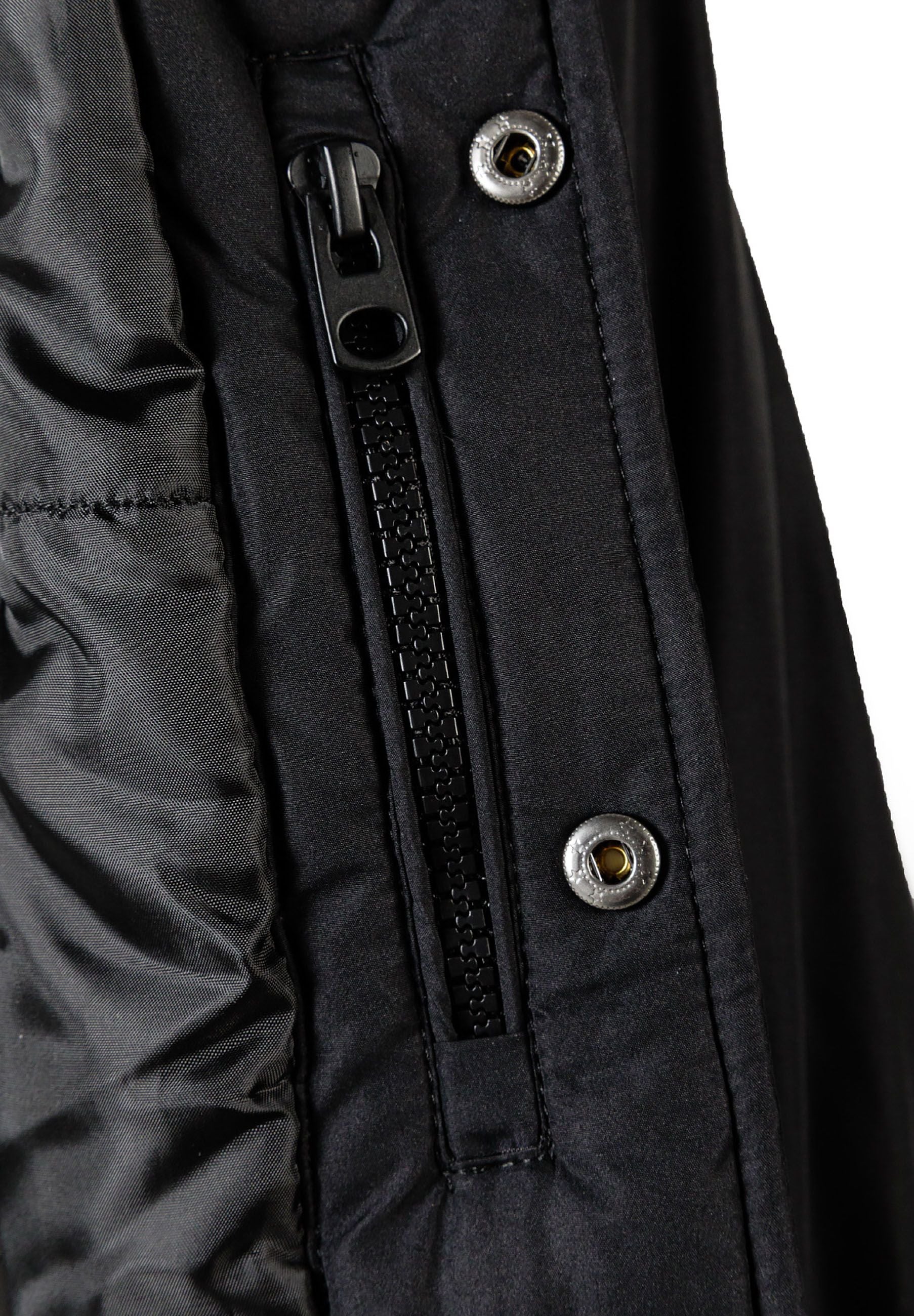 Detail of a black boys baseball jacket featuring a zipper and snap button.