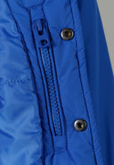Detail of a cobalt blue boys baseball style jacket with zipper and snap fastenings.