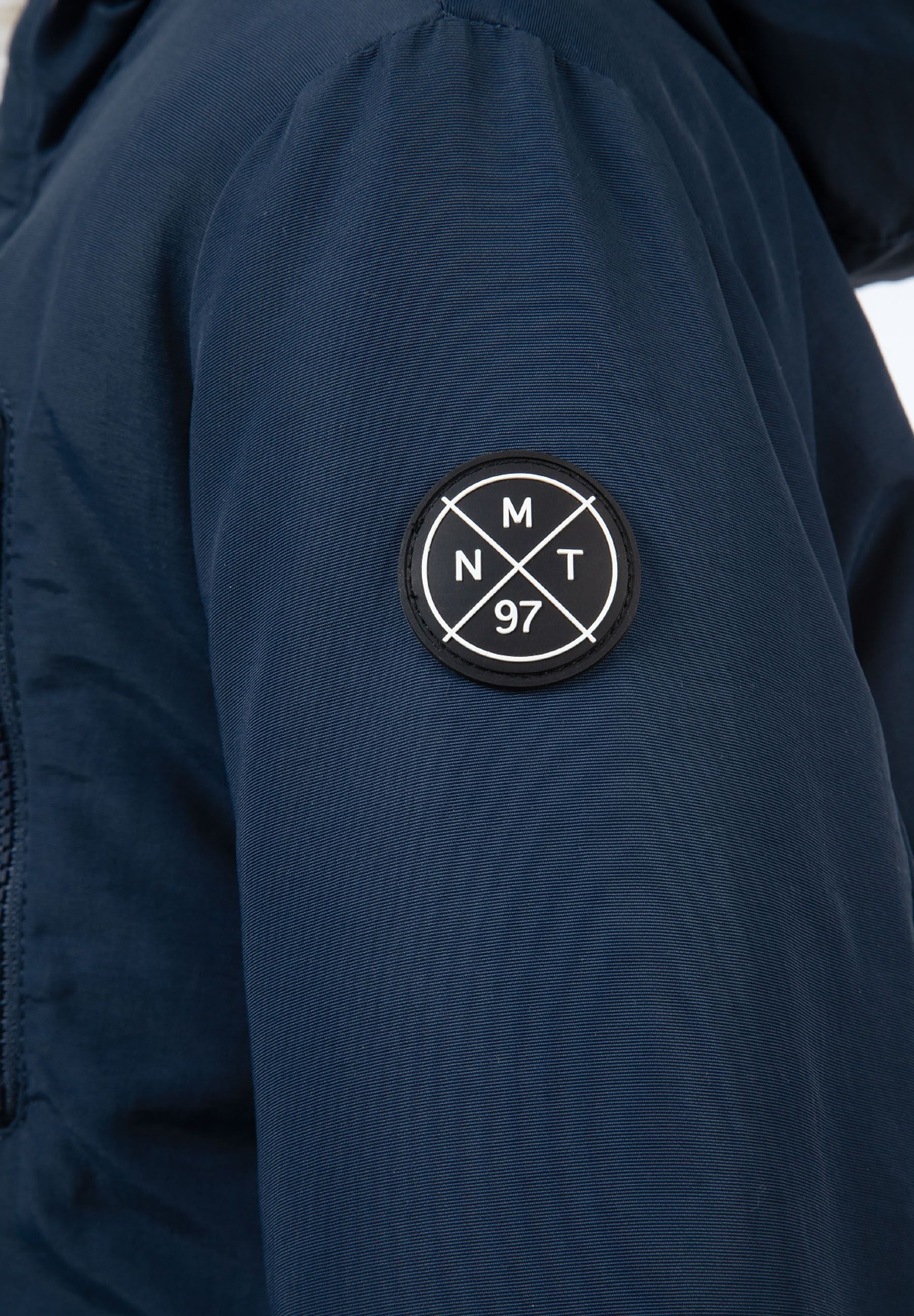 Detail of boys winter parka in navy with logo badge on sleeve.
