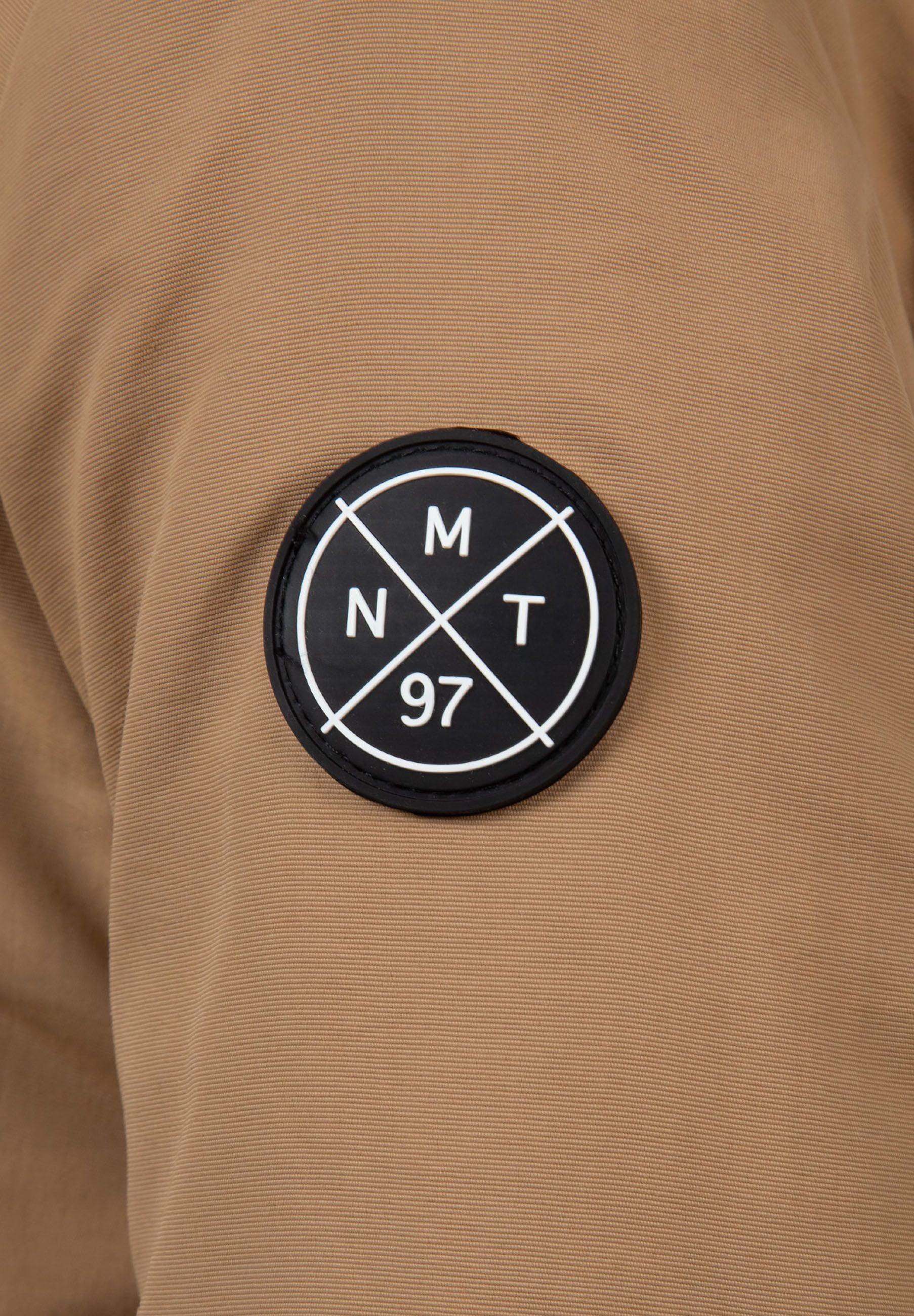 Detail of a boys winter parka sleeve with a black logo badge.