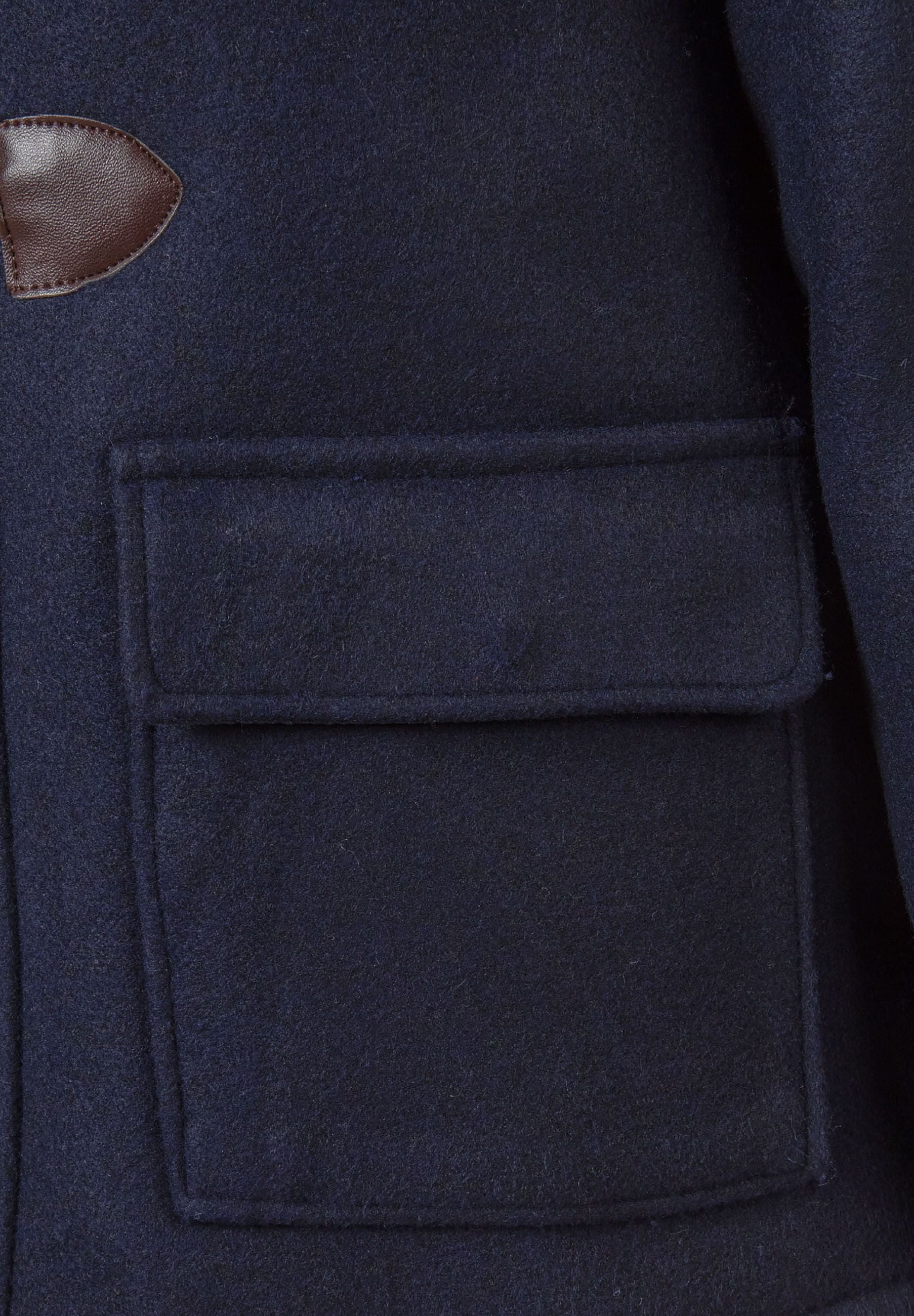 Detail of navy boys duffle coat showing toggle closure and flap pocket.