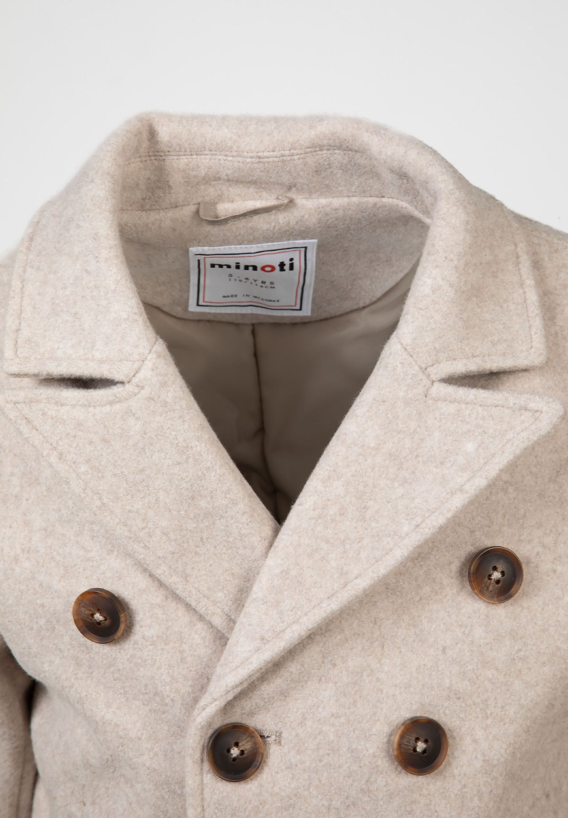 Close-up of a boys double breasted grey coat with tonal buttons and a classic lapel.
