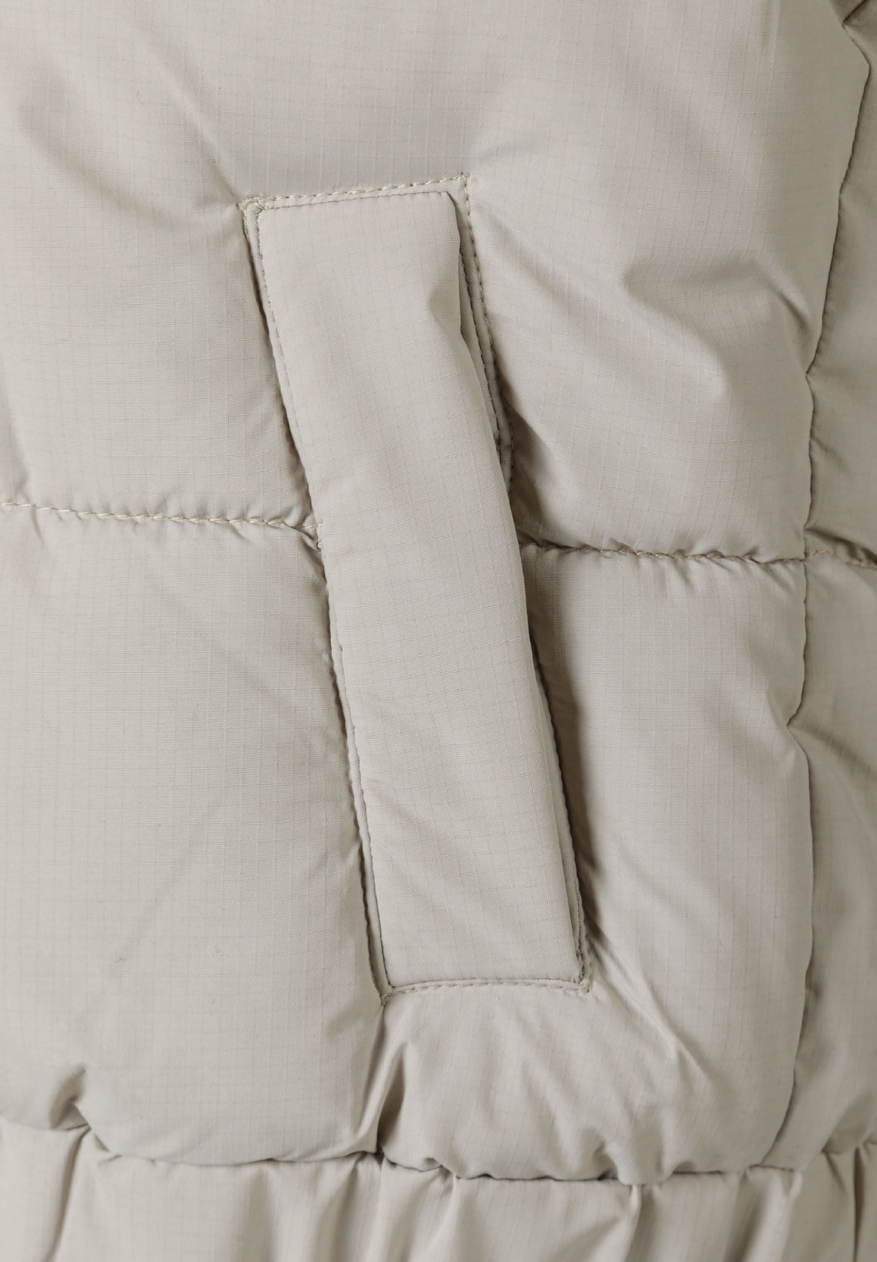 Detail of a boys padded gilet with a bungee cord trim and elasticated hem.