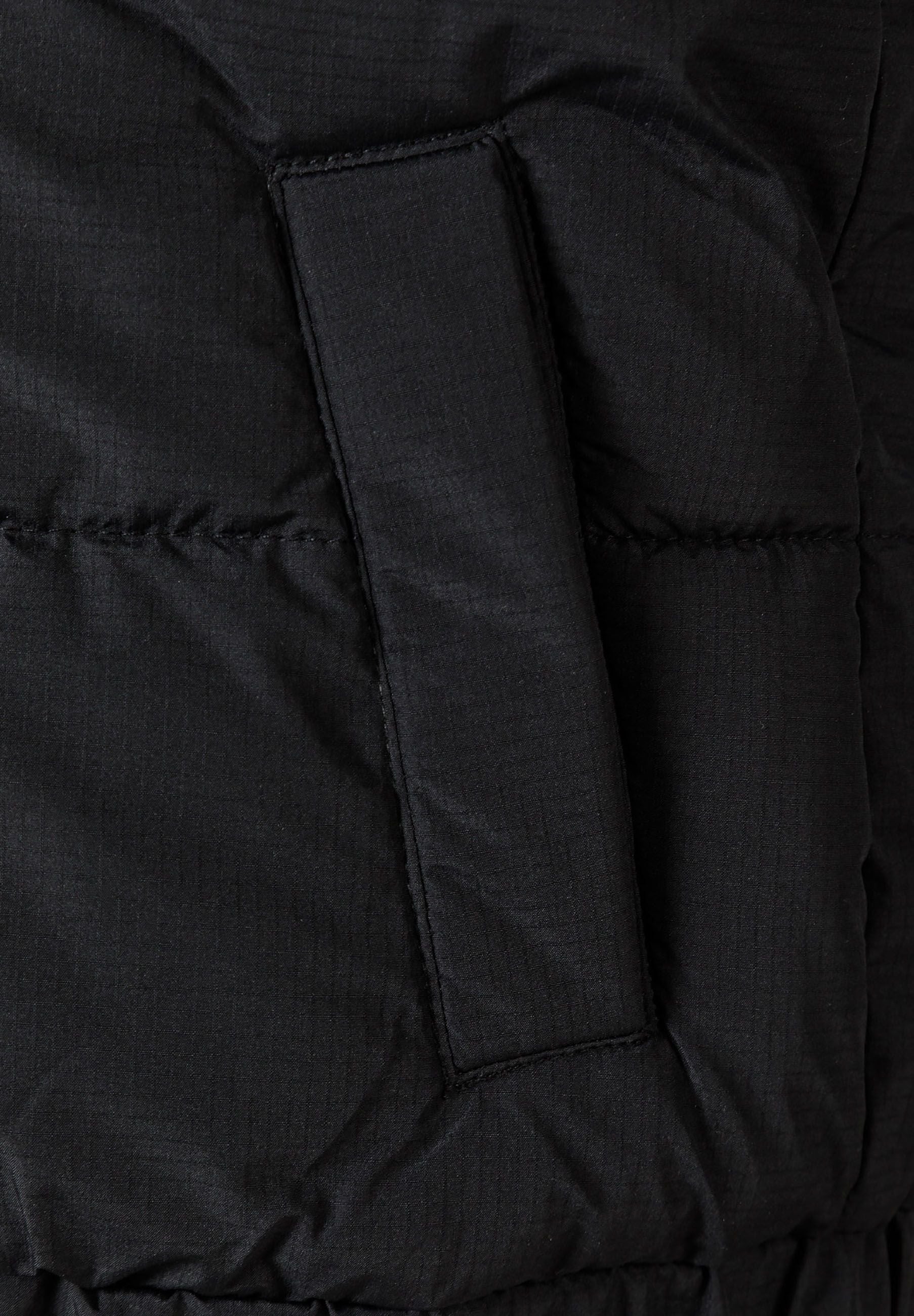 Detail of a black padded gilet featuring a side pocket and elasticated hem.
