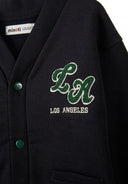 Close-up of a navy buttoned sweatshirt with chest applique and two front pockets.