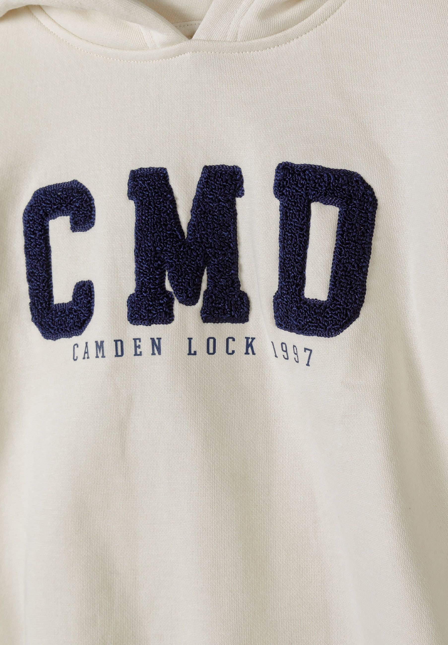 Detail of cream boys hoodie with boucle embroidery and logo.