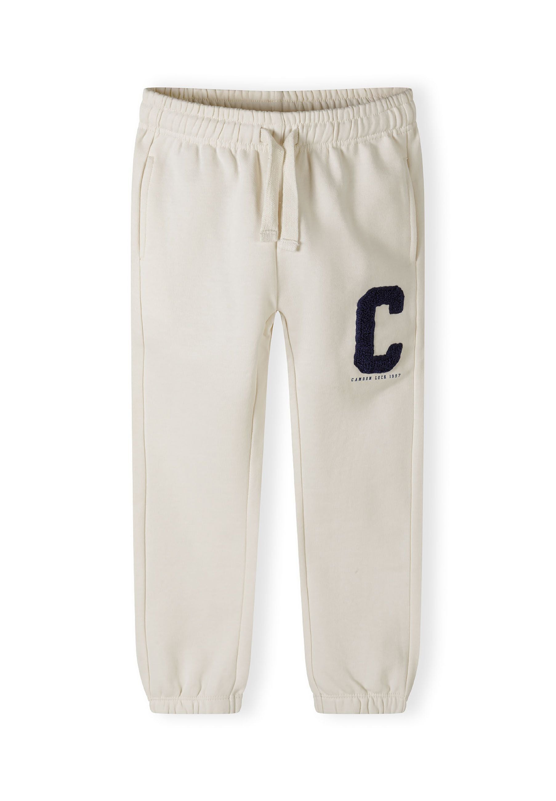 Detail of cream jogger trousers with boucle embroidery and elasticated waistband.