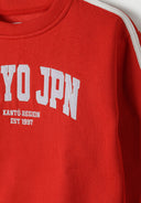 Close-up of a red boys sweatshirt featuring 'TOKYO JPN' embroidery and sporty taping.