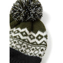 Close-up detail of black and cream fair isle knit pattern on hat with textured pom pom showing diamond and geometric designs