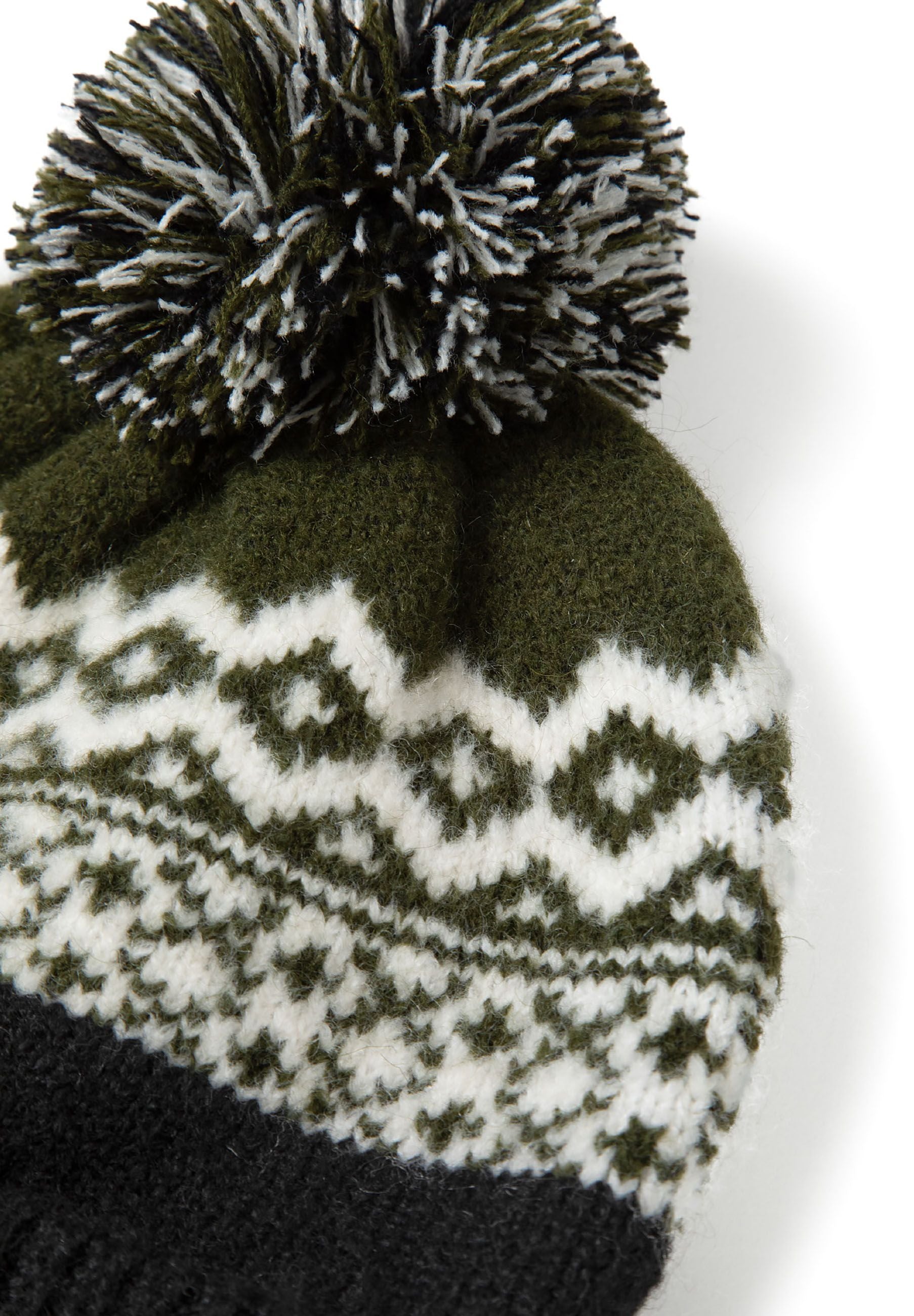 Detail of a boys' knit hat with a pompom, featuring a black and white fair isle pattern.