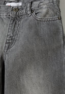 Close-up of grey baggy fit denim jeans for boys, featuring front pocket and button detail.