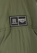 Detail of a khaki boys quilted jacket featuring a rubber logo patch.