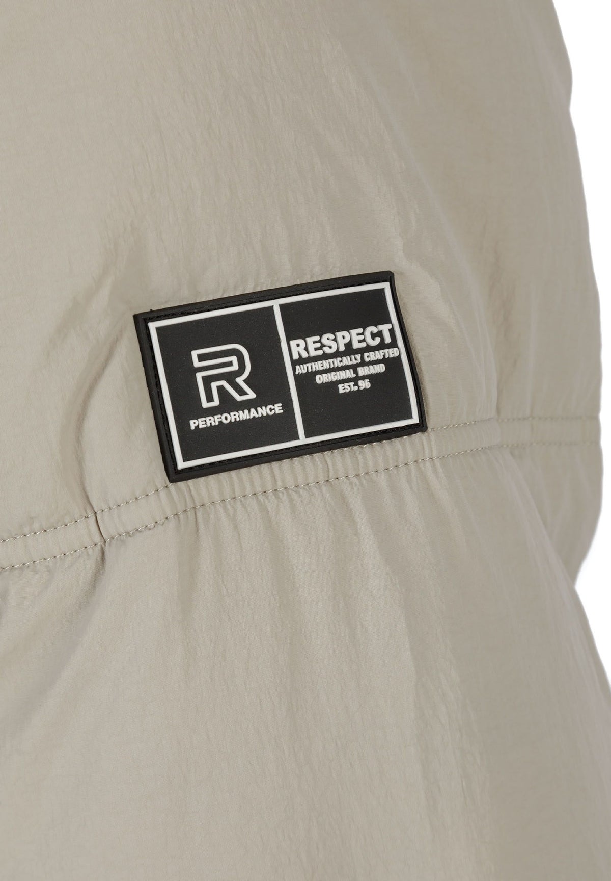 Close-up of the sleeve patch on the light beige puffer jacket.