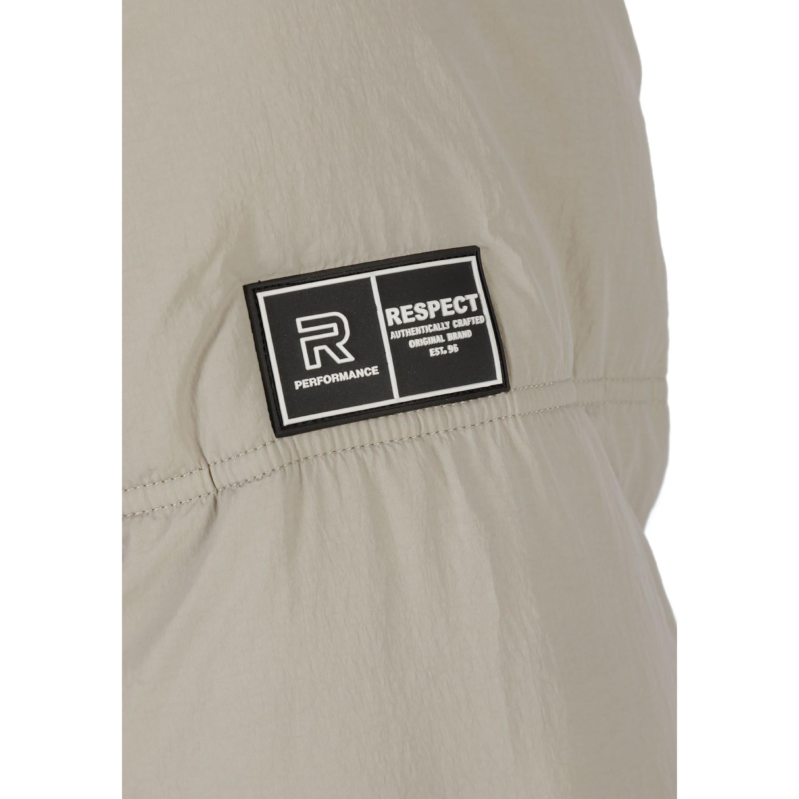 Close-up detail of grey quilted fabric showing black rectangular RESPECT logo patch with white text on jacket arm