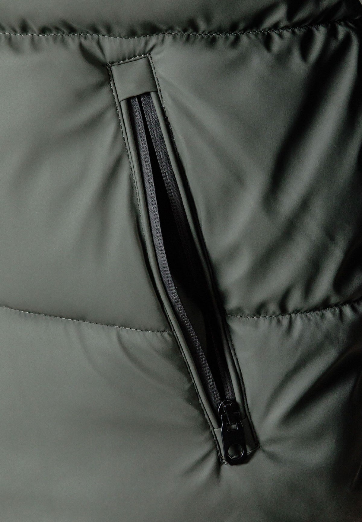 Close-up of the pocket on the dark khaki puffer jacket.