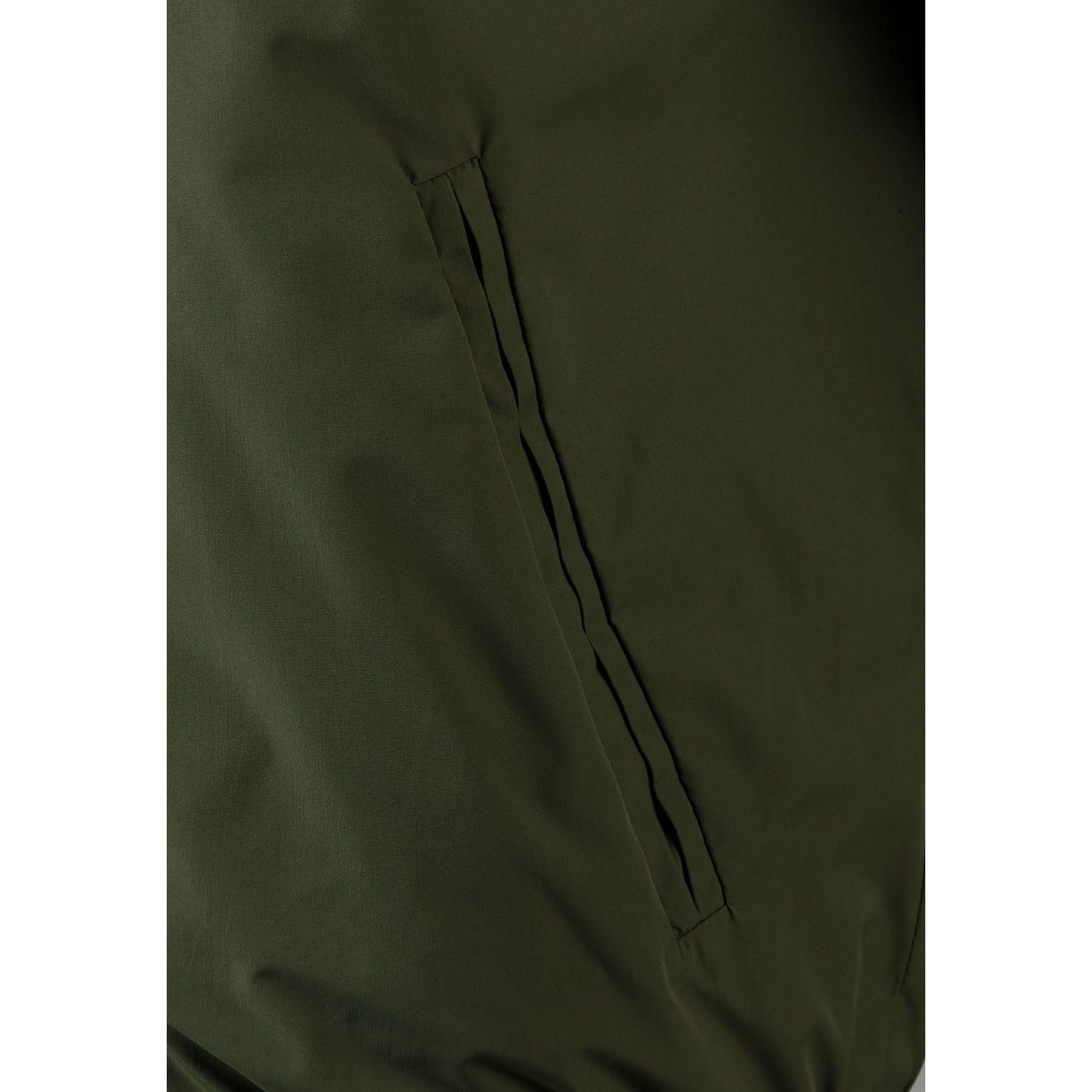 Close-up detail of khaki jacket showing zip pocket, button closure and ribbed trim construction