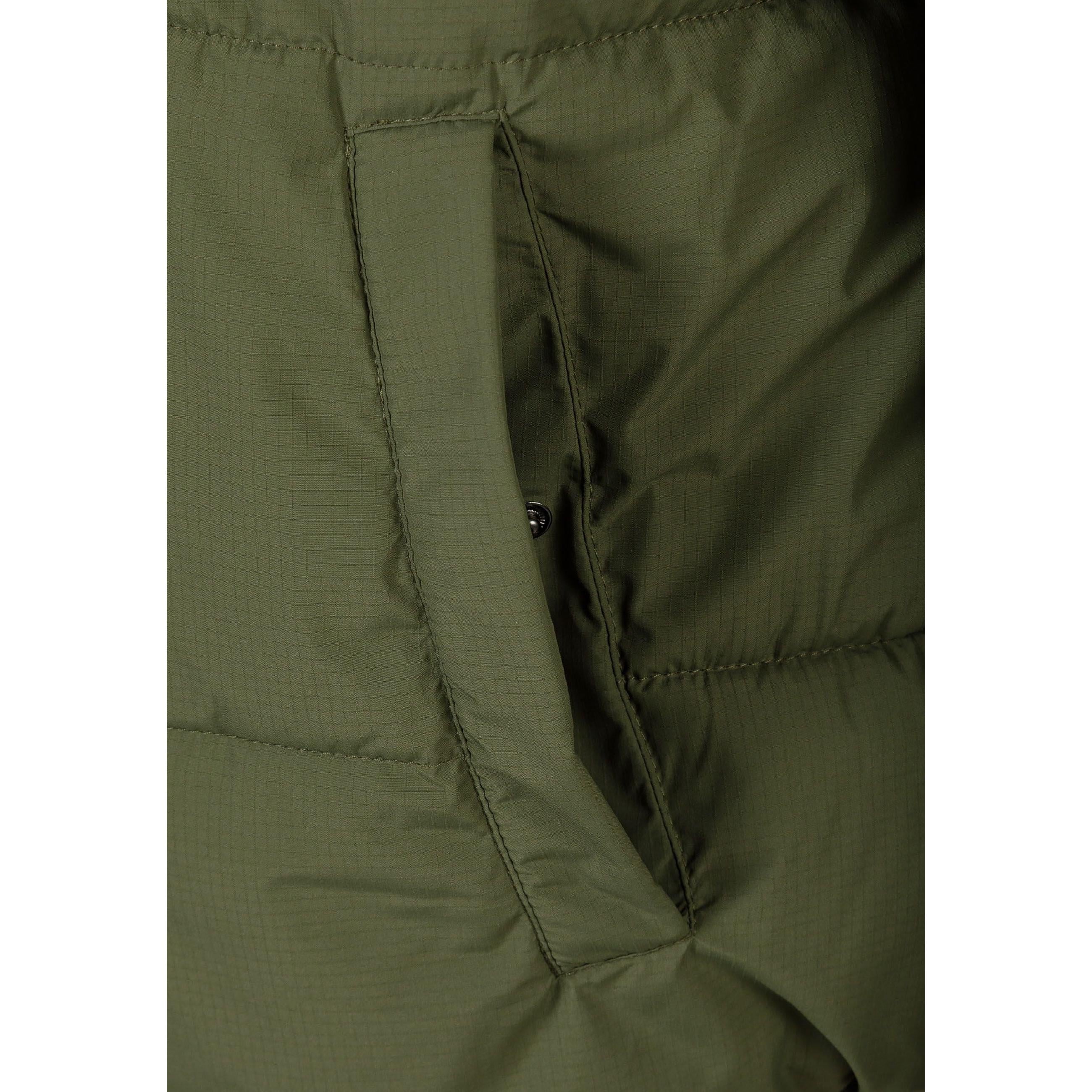 Close-up detail of black rectangular brand patch on khaki quilted jacket sleeve