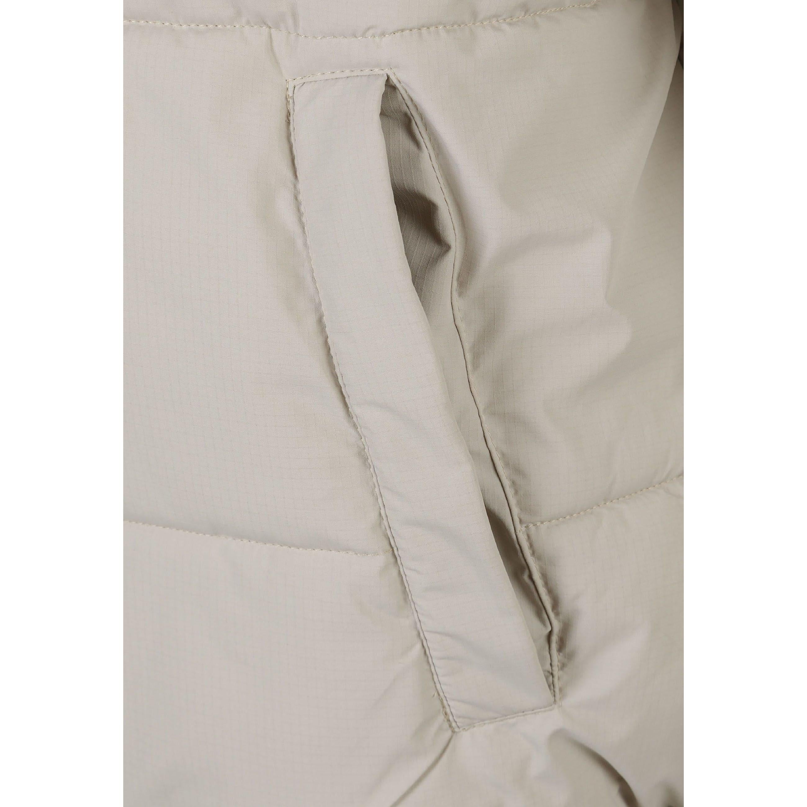 Close-up detail of black rectangular fabric label patch sewn on grey ripstop jacket sleeve showing textured fabric surface