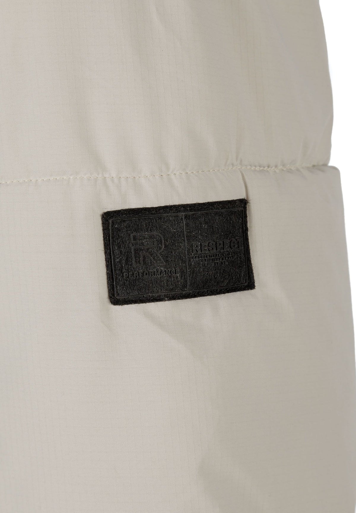 Close-up of the sleeve patch on the light beige puffer jacket.
