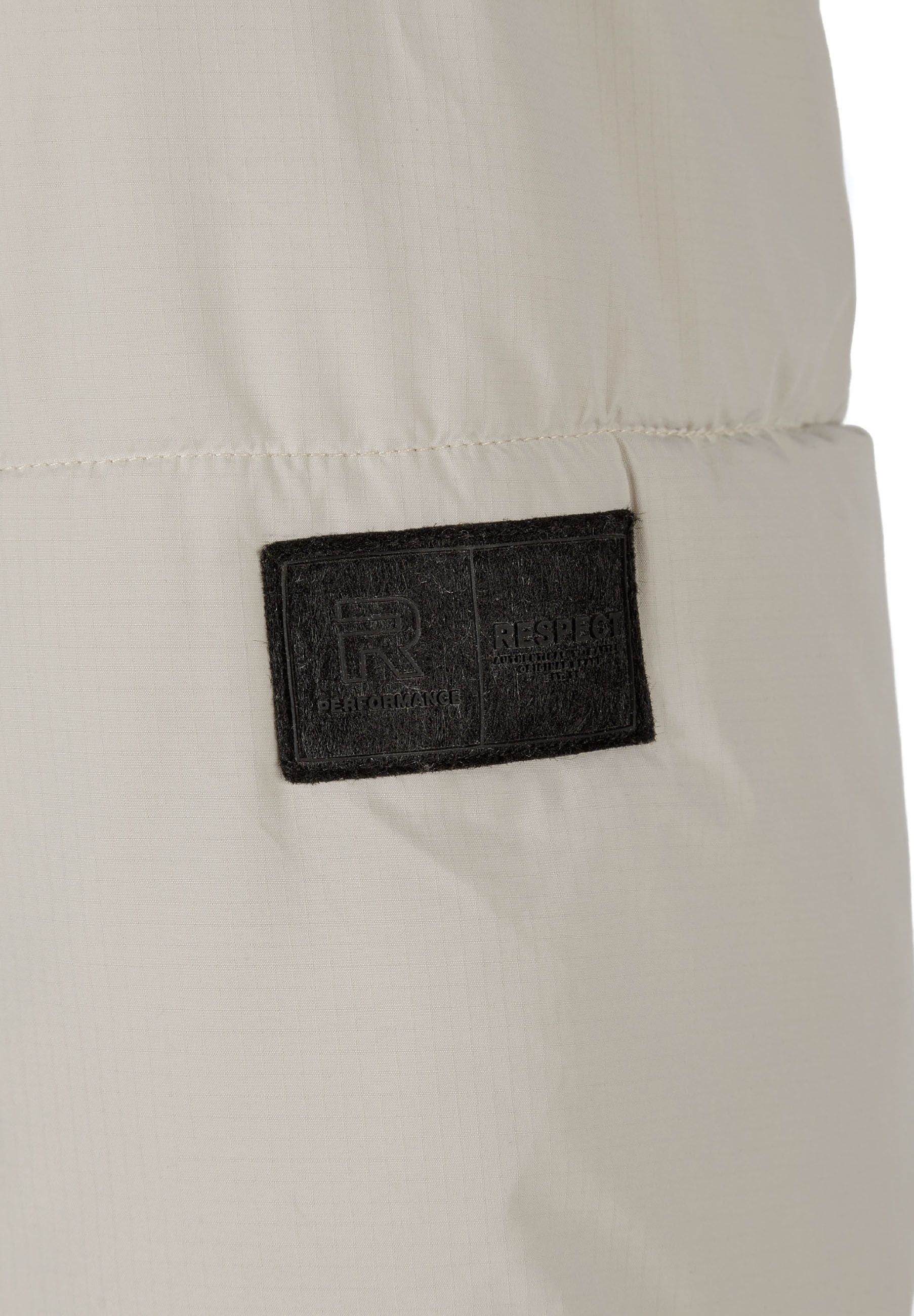 Detail of a men's ripstop jacket featuring a logo badge.