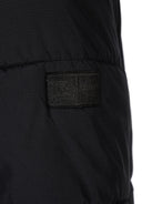 Detail of a black ripstop jacket featuring a logo badge.