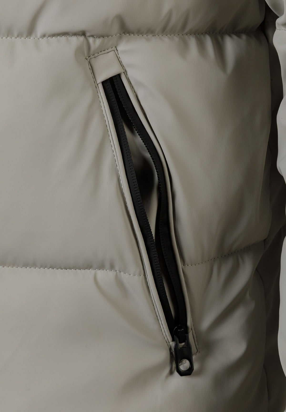 Close-up of the pocket on the light grey puffer jacket.