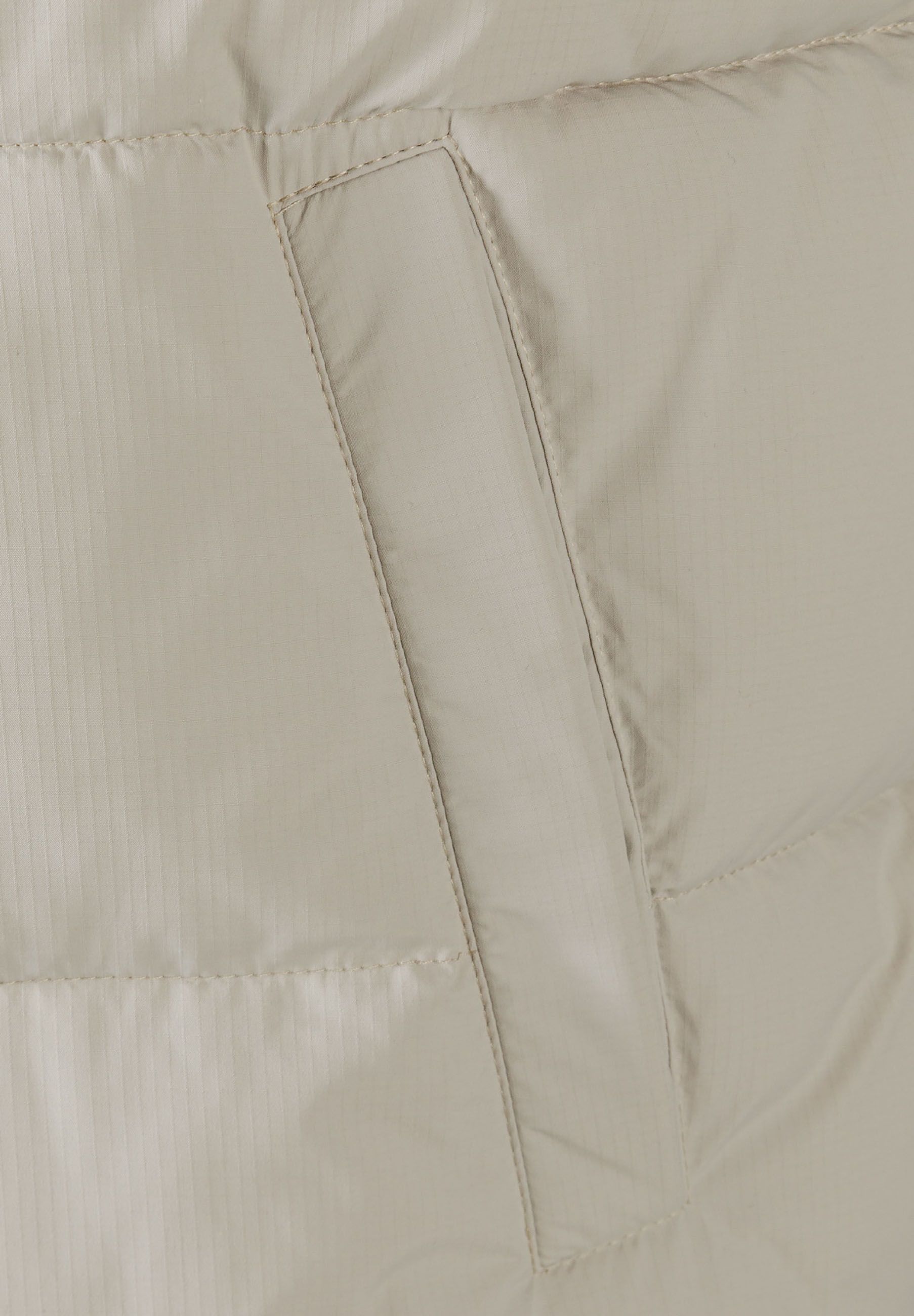 Detail of men's padded gilet with horizontal quilting and side pocket.