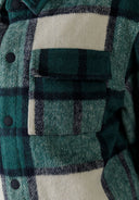 Detail of a boys padded shirt jacket in green check pattern with a patch pocket.