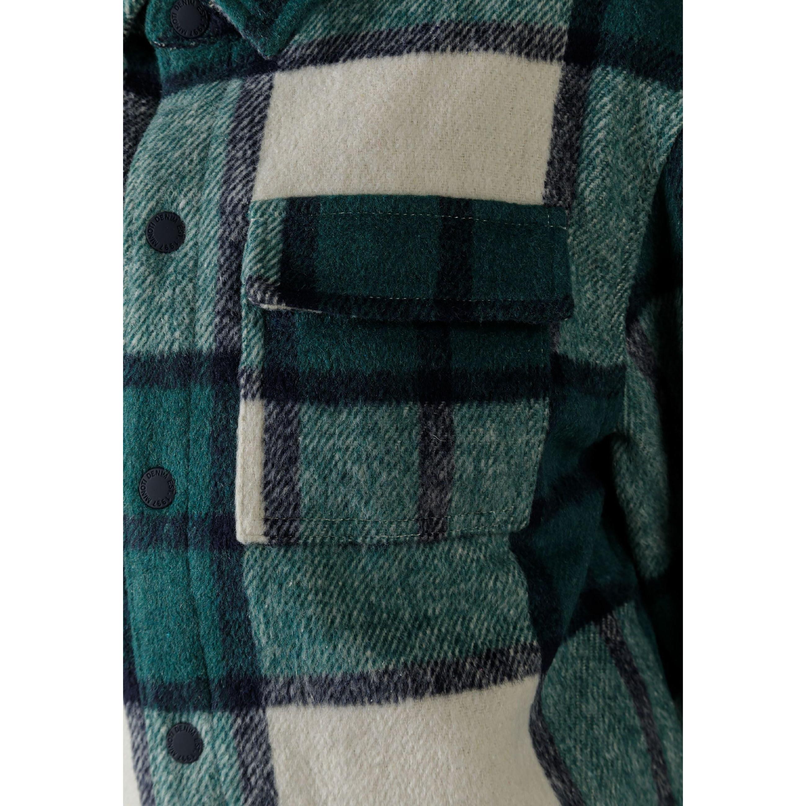 Close-up detail of green check shirt jacket showing chest pocket, button placket and quilted fabric texture with plaid pattern