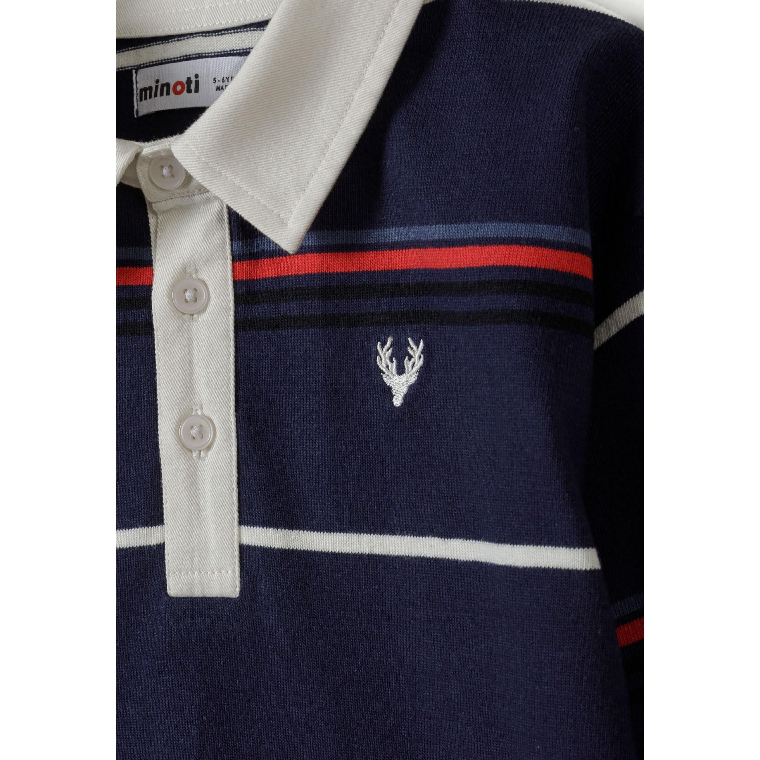 Close-up detail of polo shirt showing white collar, button placket, embroidered white stag emblem and Minoti label